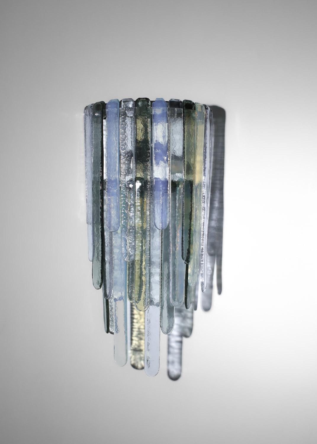 Pair of very large wall sconces from the 70's by Italian designer Carlo Nason for Mazzega. Chrome-plated metal structure and wall plate, shade in thick glass in various colors (blue, gray, transparent and smoked). Possibility of changing the