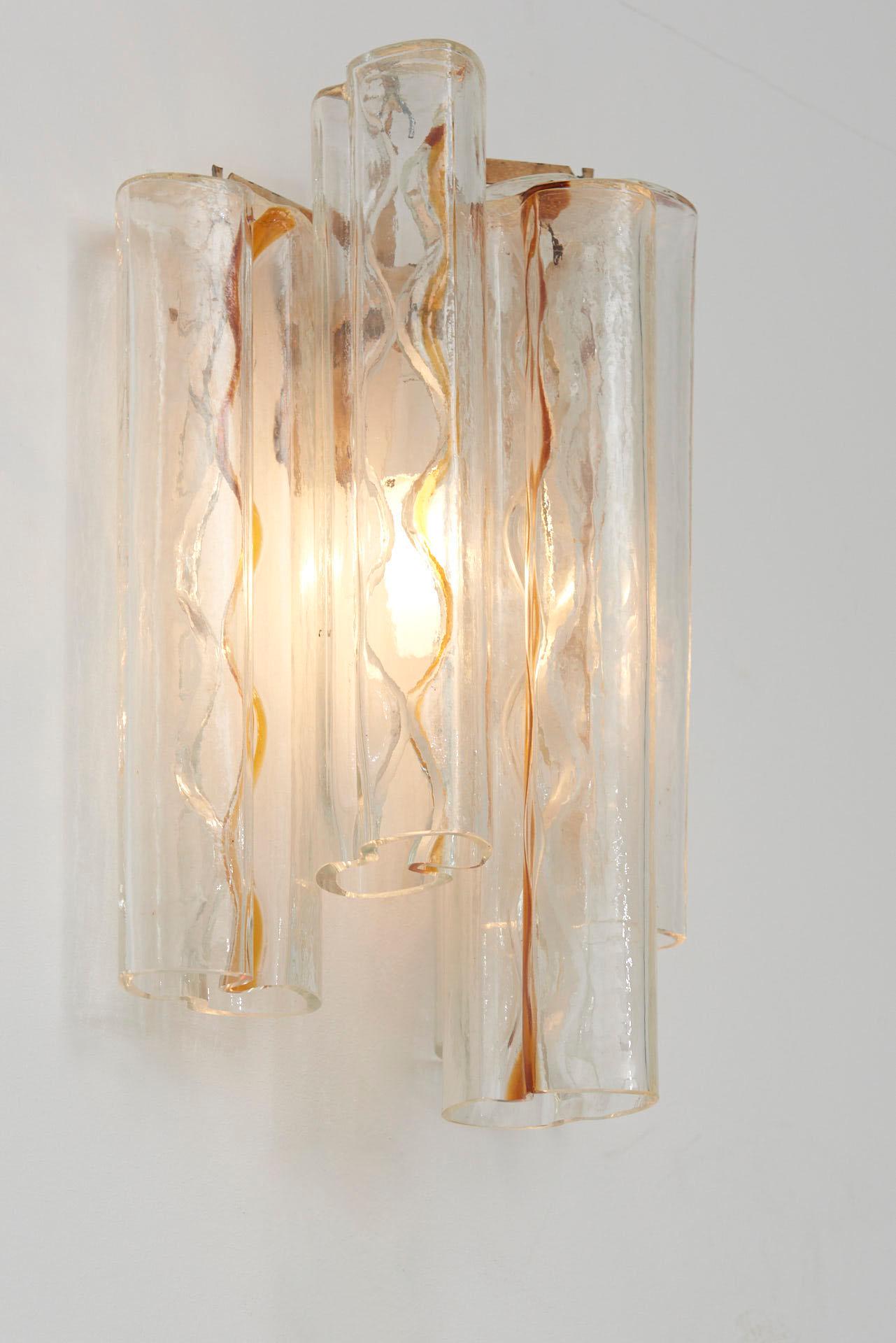 Pair of large Italian wall sconces, designed by Toni Zuccheri for Venini.
Four Murano glass tubes with bow-shaped section and orange lines are suspended on a steel frame. One bulb connected to the frame lights up the tubes.