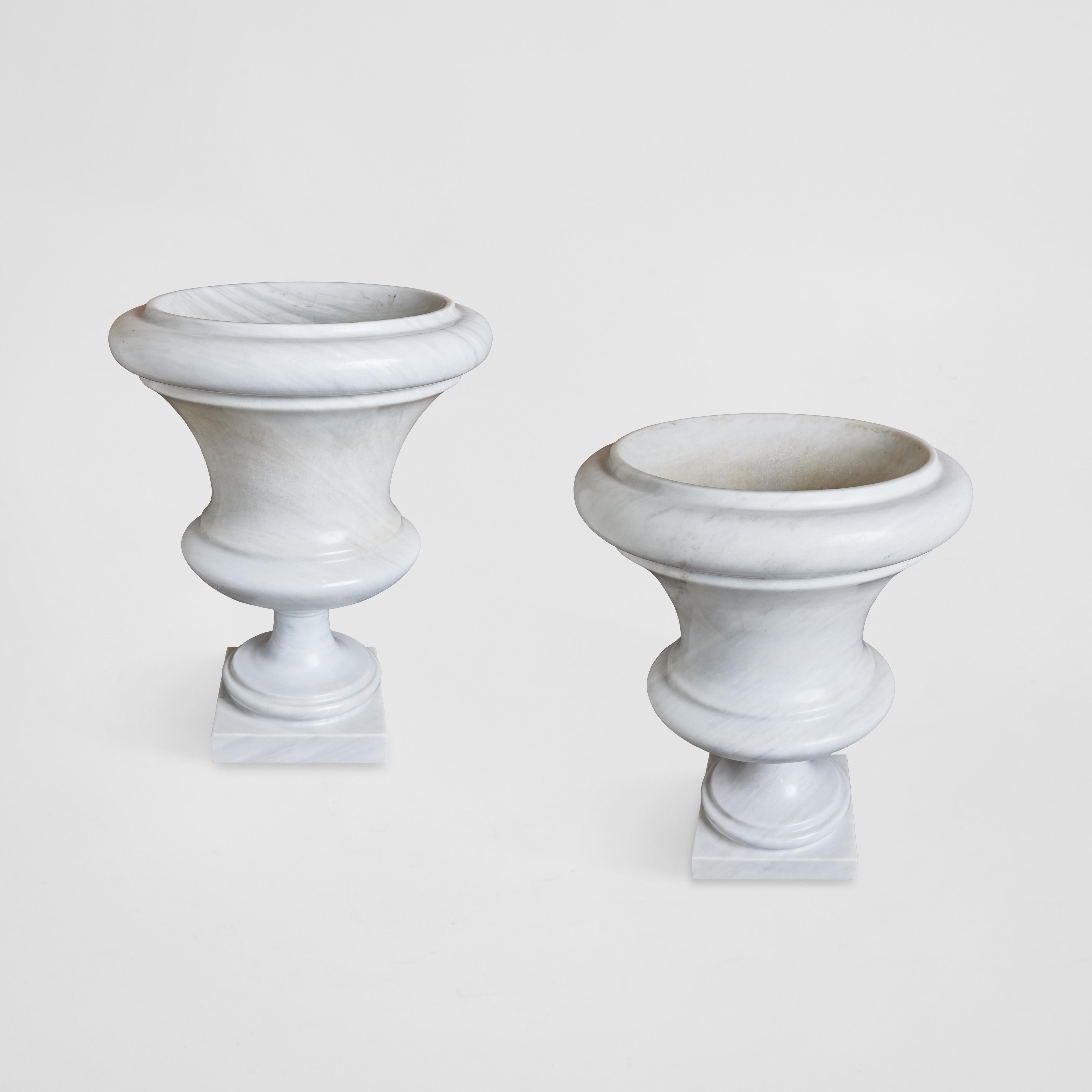 Großformatiges Paar klassischer weißer Karrara-Urnen.  Diese Urnen können sowohl für den Innen- als auch für den Außenbereich verwendet werden. Sie sind wunderschön als Solitär, gepflanzt oder mit weißen Orchideen gefüllt.