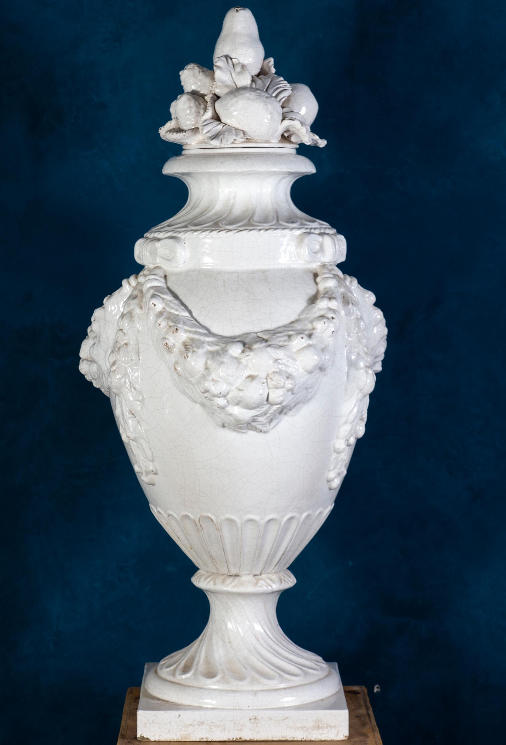 A pair of large Italian white ceramic urn vases with fruit and leave garlands. 
Manufactory of Bassano del Grappa.
 Early 20th century.
 Elegant decoration for you interior or garden.
Cm 120 x55.