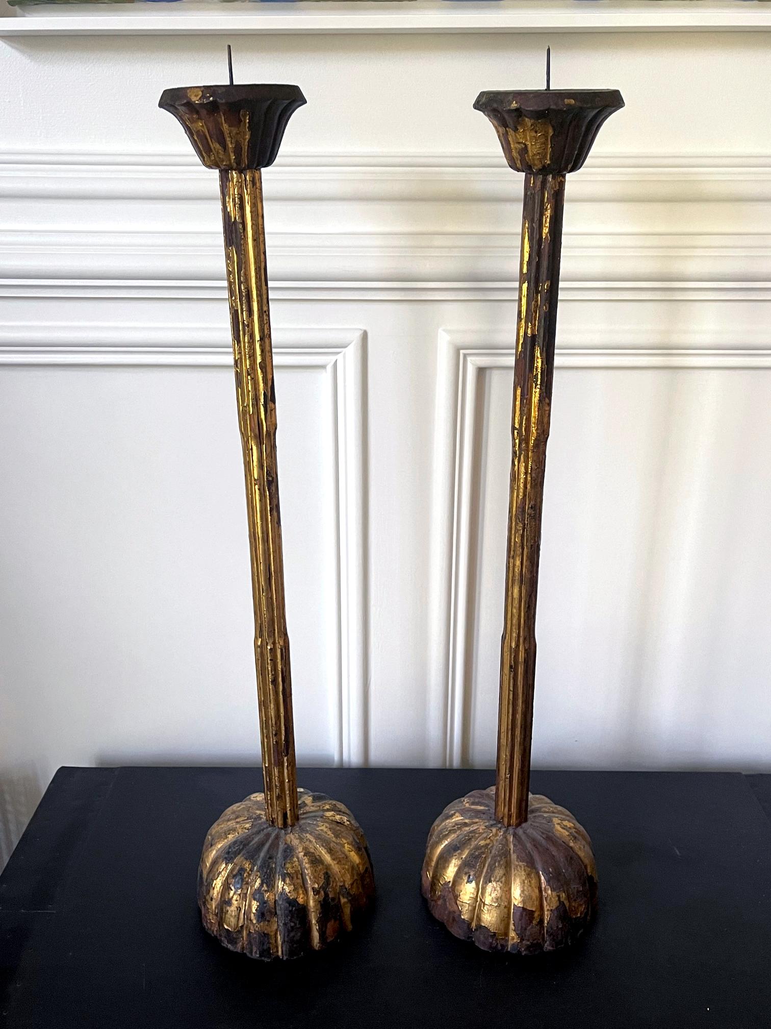 A tall pair of Japanese carved wood candle holders circa early 19th century (late Edo Period). The pair is carved in the typical form with a block base in the shape of stylized chrysanthemums and long fluted stem with changes in diameter that