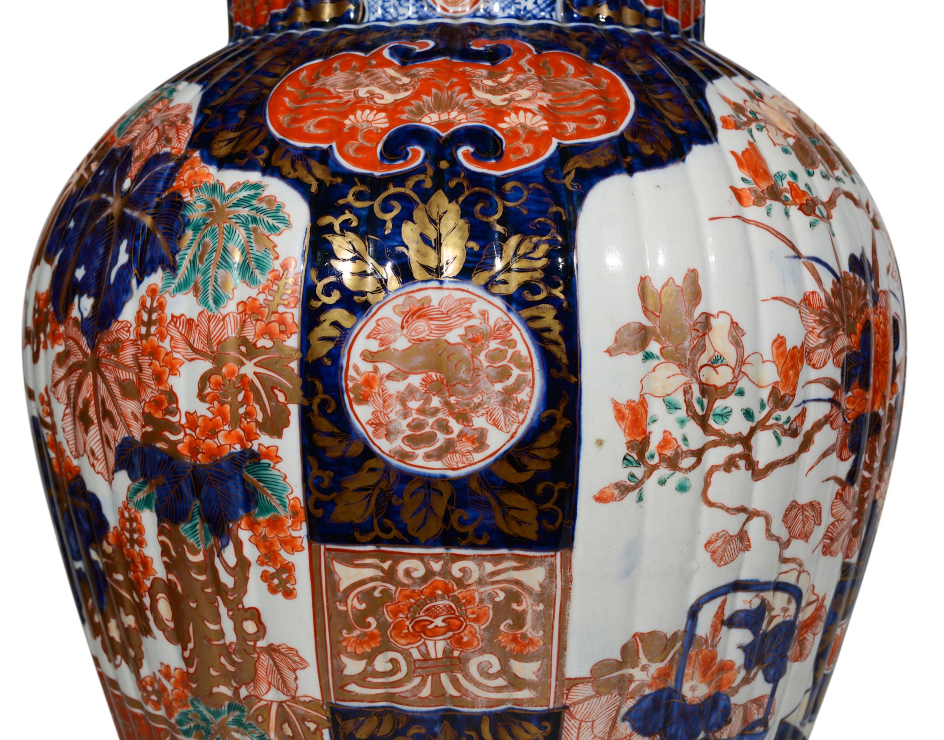 Superbe paire de grands vases japonais Imari du XIXe siècle, décorés dans la palette typique de bleus foncés et de rouges de fer sur fond blanc avec des reflets dorés, les panneaux principaux représentant de grandes compositions florales dans un