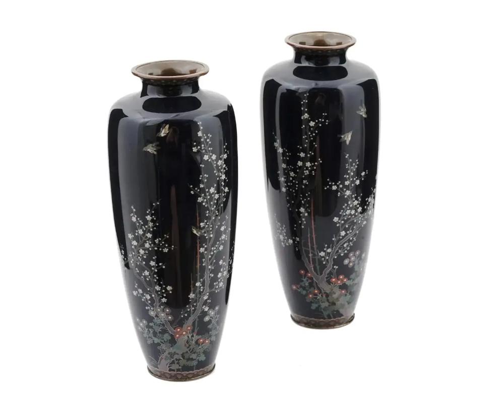 A pair of large antique Japanese Meiji Era enamel over brass vases attributed to Hayashi Kodenji, Japanese, 1831 to 1915. Circa: 1900s. Unsigned. The baluster form vase is enameled with polychrome images of gold sparrows in blossoming flowers made