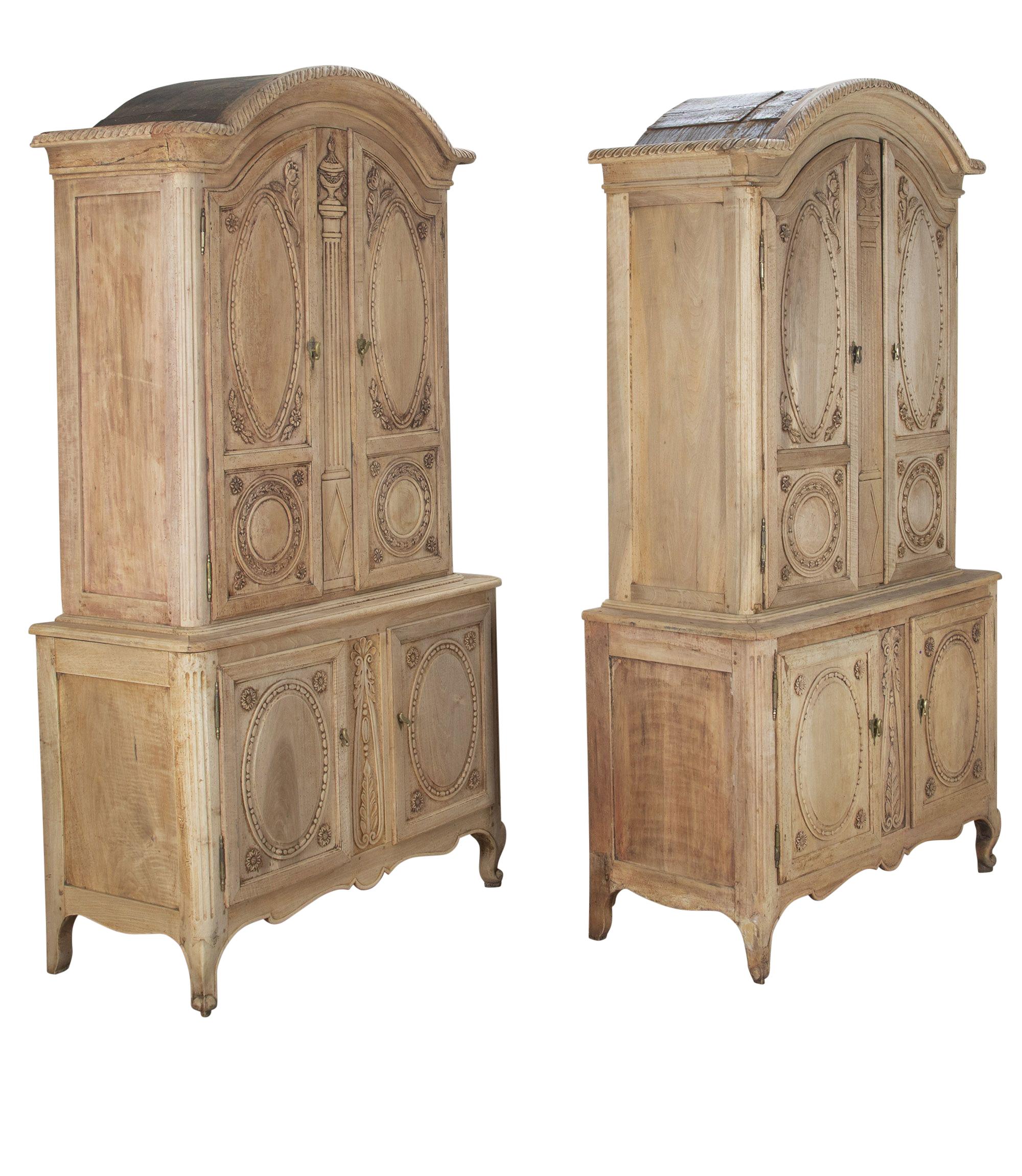 Pair of late 19th Century French bleached cabinets.
Below the pediment, two doors with Neo-Classical carved detailings opening to useful storage. Below, two further carved doors. Bleached exteriors and repainted on the interior. Will separate into