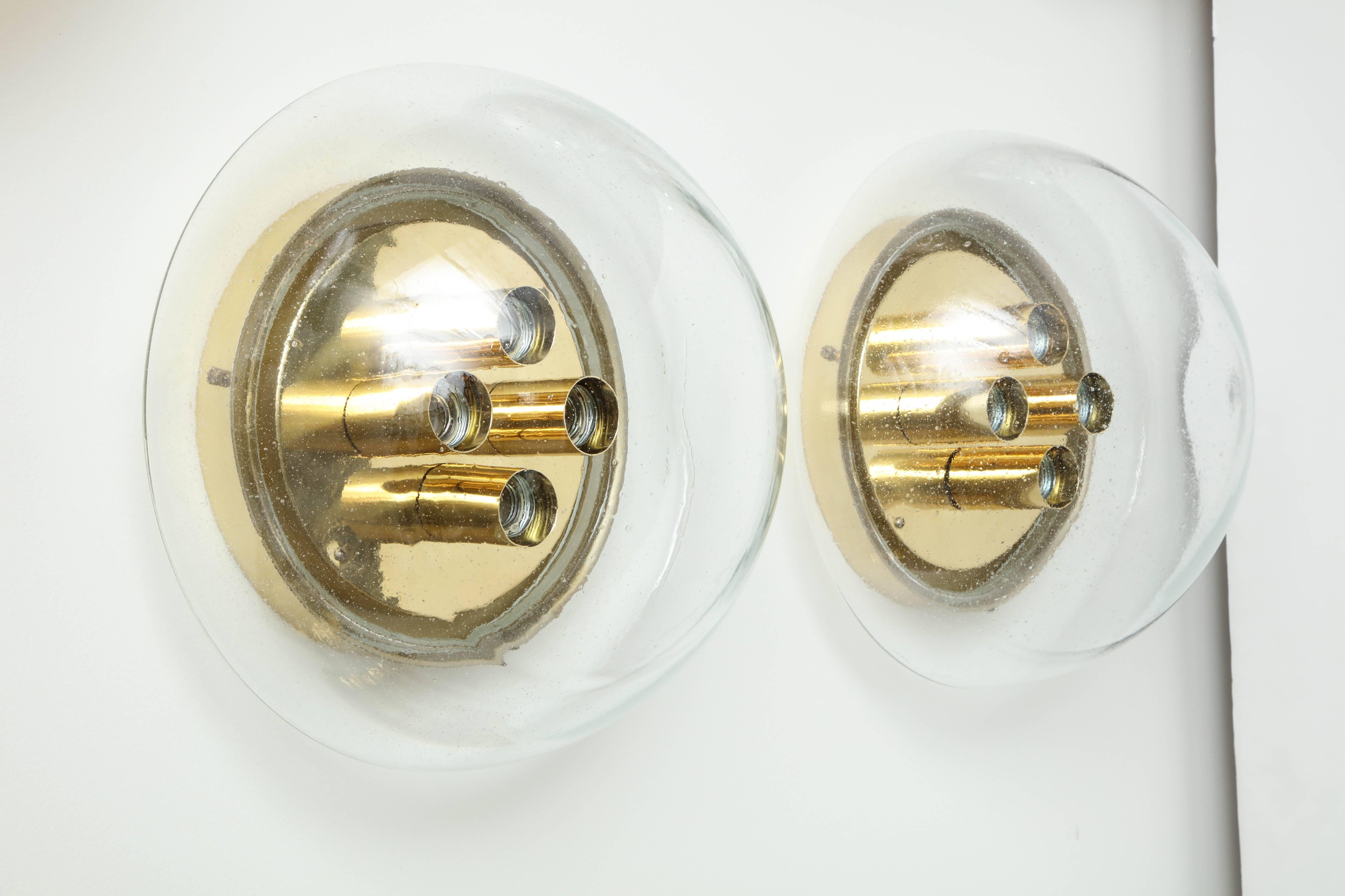 Large pair of glass flush mounts / sconces by Limburg.
The large bubble glass element is supported by a polished brass plate with four light sources that has been newly rewired for the US.
There are two pairs available and they are priced at $3200