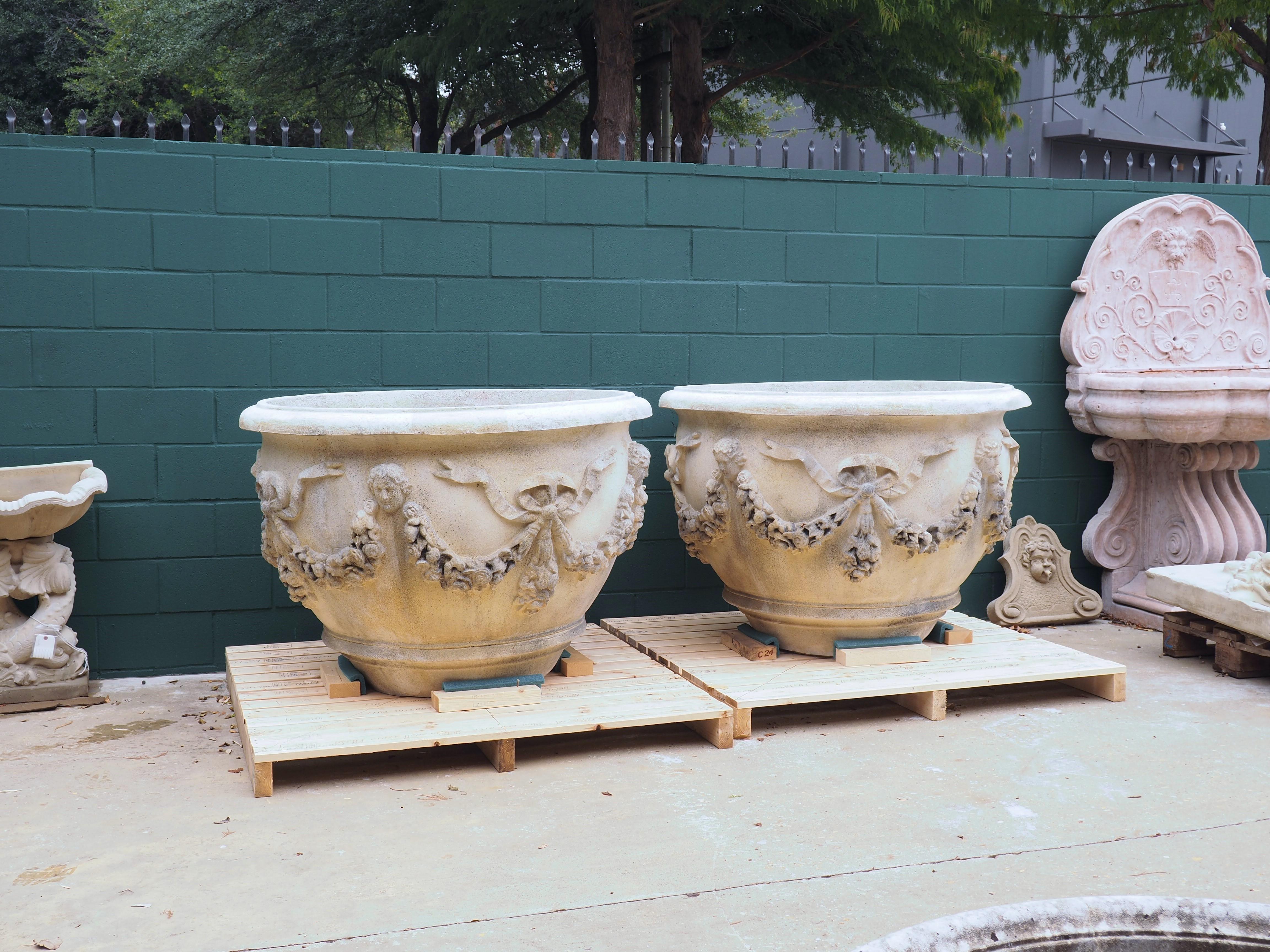 With a max diameter of over 52 inches, this pair of French cast stone planters are large enough to accommodate anything from multiple plants up to single trees. The lip surrounding the opening has a thick and recessed quarter round molding, which