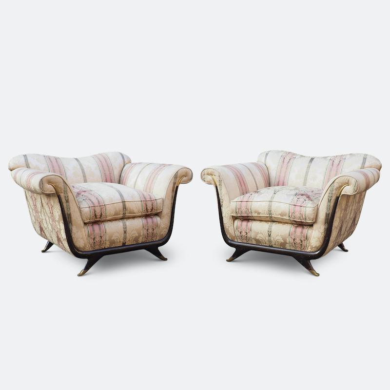 A pair of large lounge chairs attributed to Italian designer Guglielmo Ulrich, Circa 1940. 
Of gracefully sculptural form with sweeping arabesques finished and with brass finials and sabot feet, these sumptuously upholstered chairs come in their
