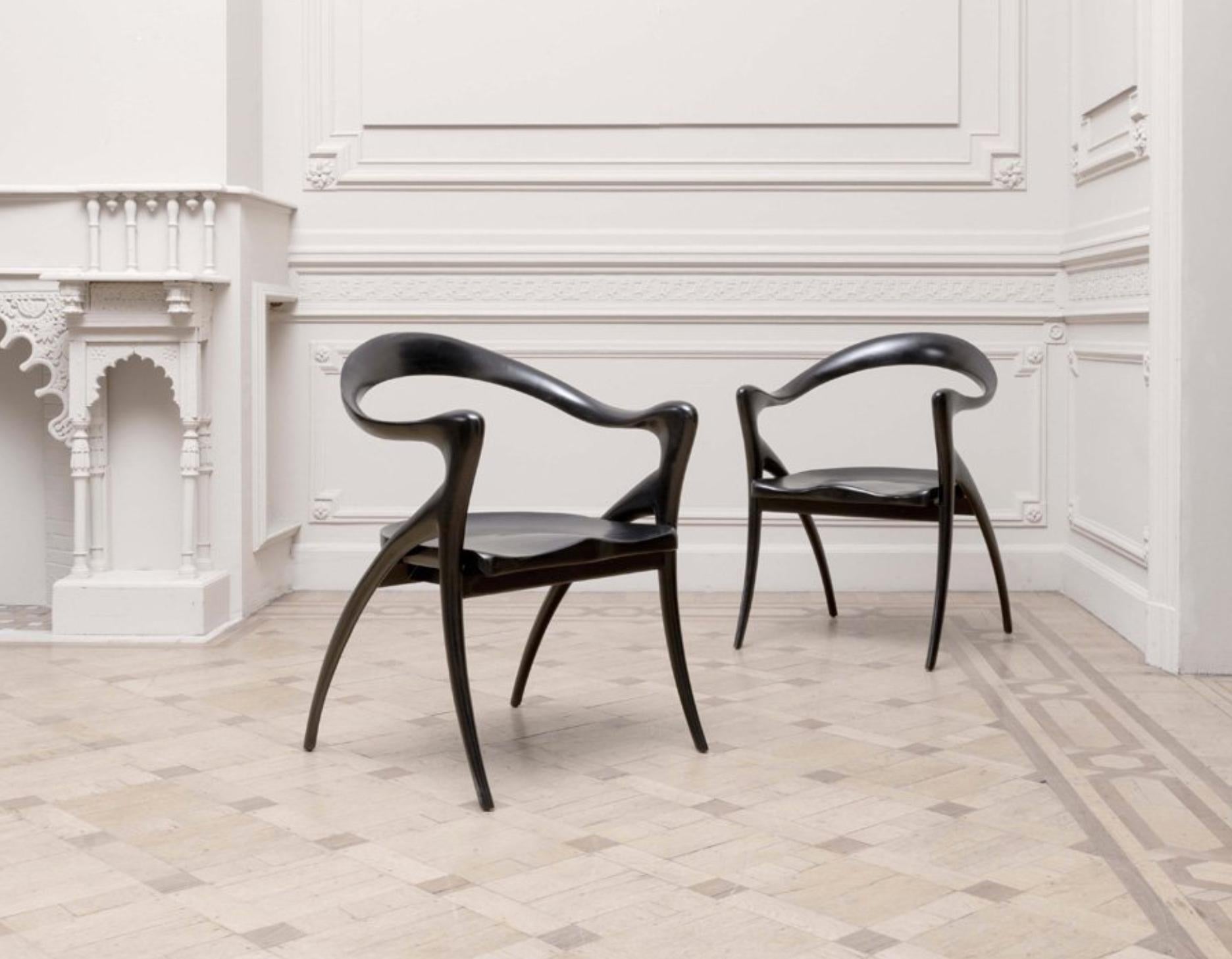 Grands fauteuils d'Olivier de Schrijver (né en 1958) en couleur noir satiné.
Modèle Ode à la femme avec bandeau ondulé en acajou prolongé par les accoudoirs et la base, sièges incurvés.