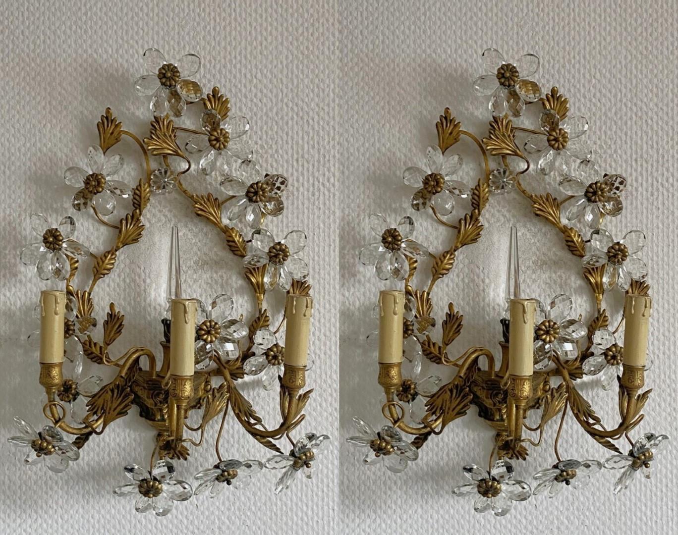  Amazing, rare pair of large Maison Bagès gilded wrought iron three-arm wall sconces, France, 1930s. Wonderful handcrafted  gilded wrought iron leaf environment, enriched with clear faceted crystal flowers and a crystal obelisk in the center,