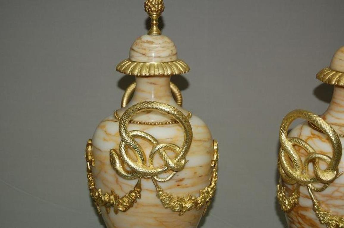 Important pair of covered vases in yellow Siena marble and chiseled and gilded bronze mount. Snake handles and flower garlands, ribbons, pearls, gadroons and acanthus leaves. Late 19th century period. In a perfect state.