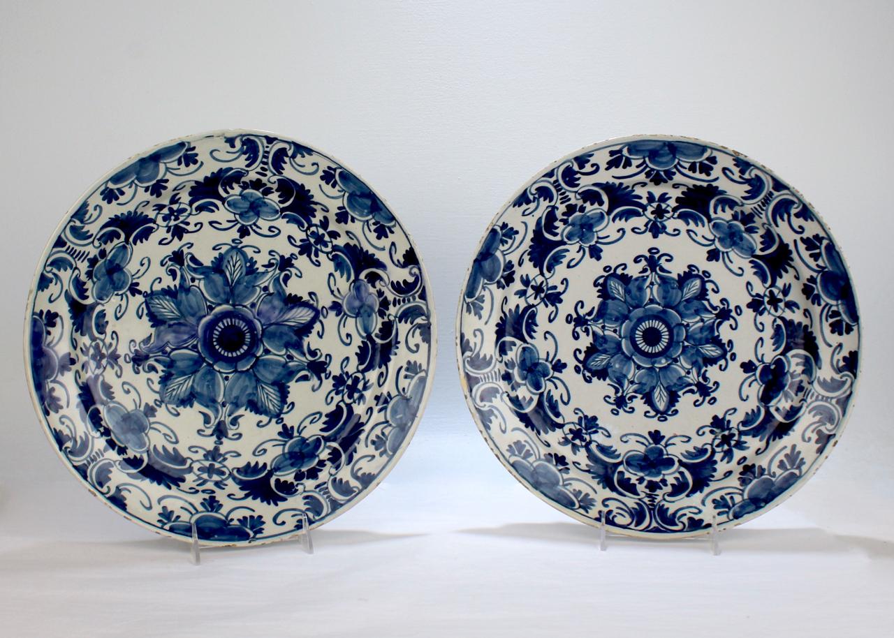 A very fine pair of large, matched Dutch delft pottery chargers or wall plates.

Dating to the 18th century.

With a stylized blue starburst floral device at the center and a richly decorated blue border.

Measure: Diameter ca. 13 5/8
