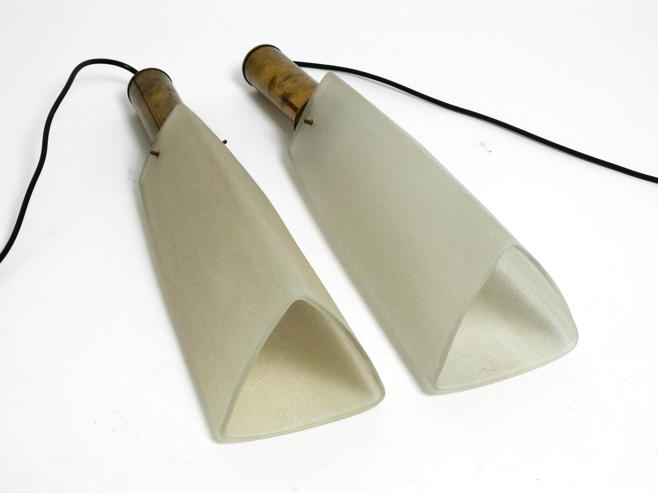 Two beautiful very rare Mid Century Modern brass pendant lamps with long triangular glass lampshades. From a Danish production.
On both original sockets is written 