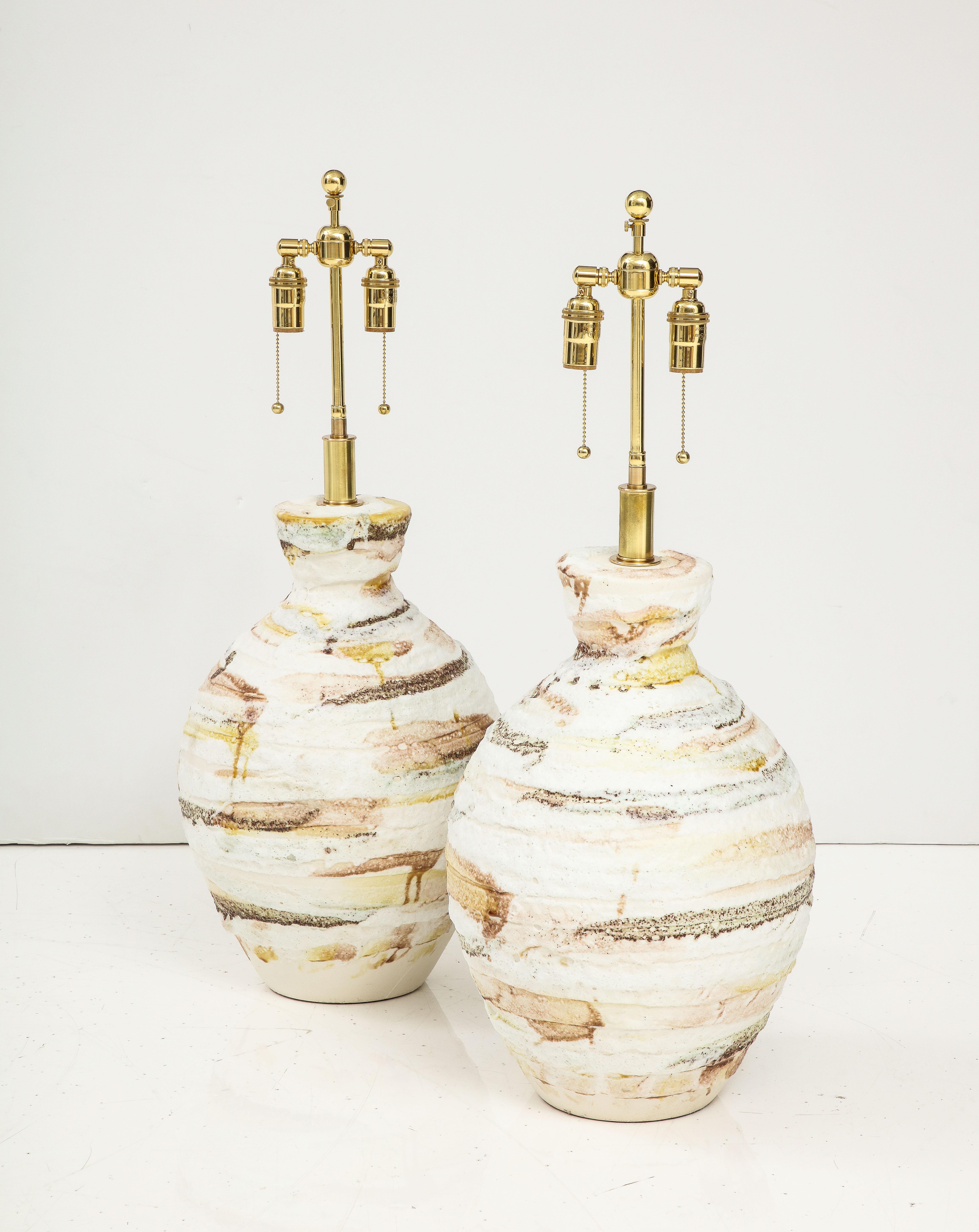 Pair of Large Italian Ceramic lamps with a volcanic textured finish.
The lamps have been Newly rewired with adjustable polished brass double
clusters that take standard size light bulbs and silk Rayon cords.
60 watts per socket 120 Watts Maximum per