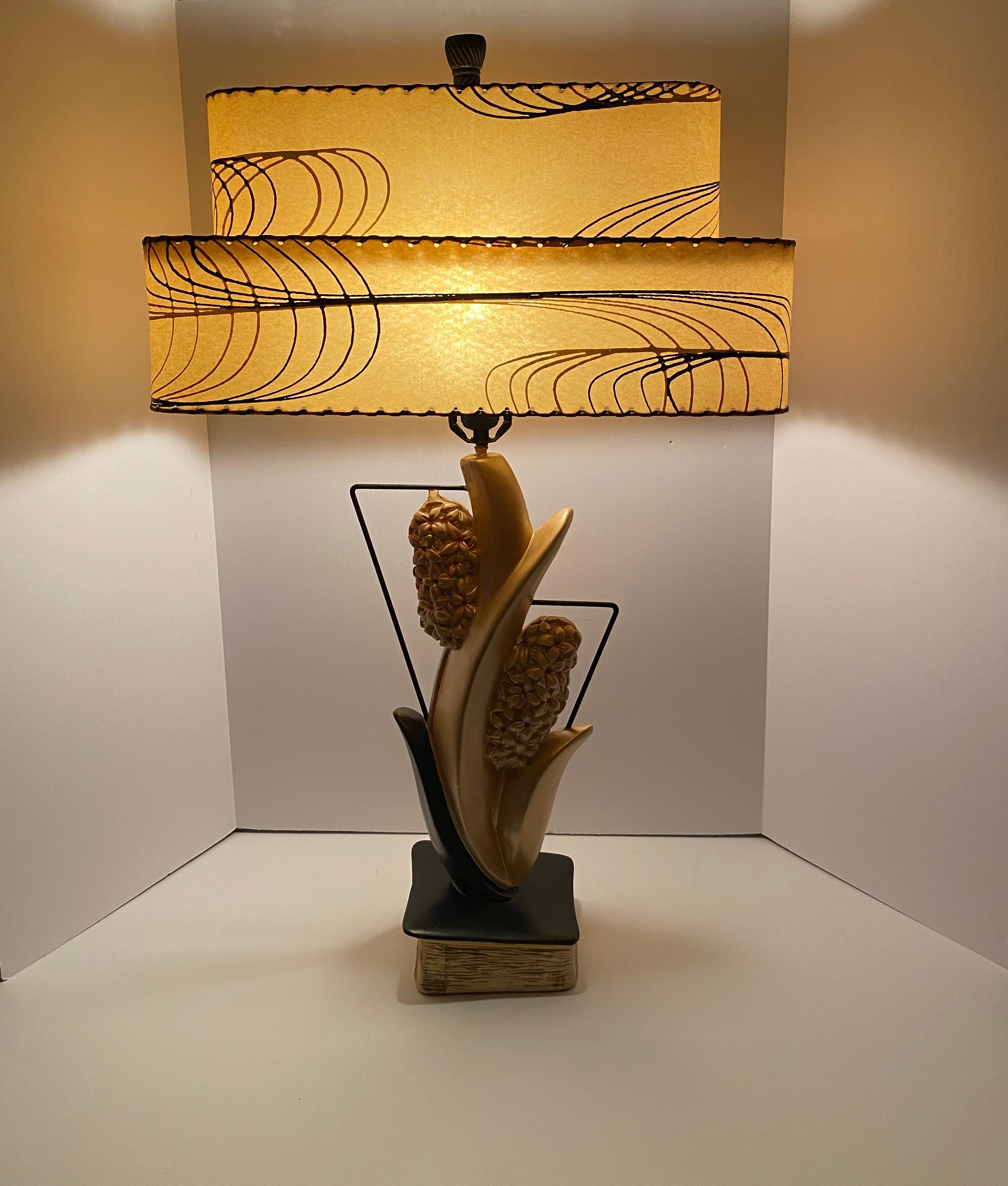 Illuminate your space with this captivating large pair of mid century table lamps with fiberglass shades. The nature-inspired design seamlessly blends with contemporary elegance. Crafted with precision, these exceptional table lamps are composed of