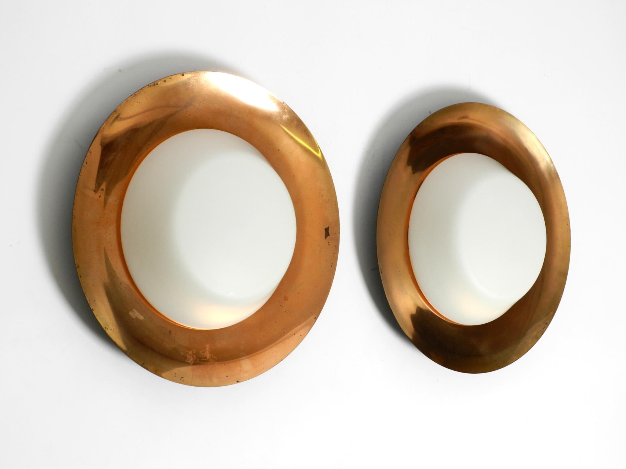Pair of large Mid Century wall or ceiling lamps made of glass with copper-plated metal reflector.
Great minimalist, typical 1950s design. Manufacturer is Kaiser Leuchten. Made in Germany.
The front side is coated with a layer of copper.