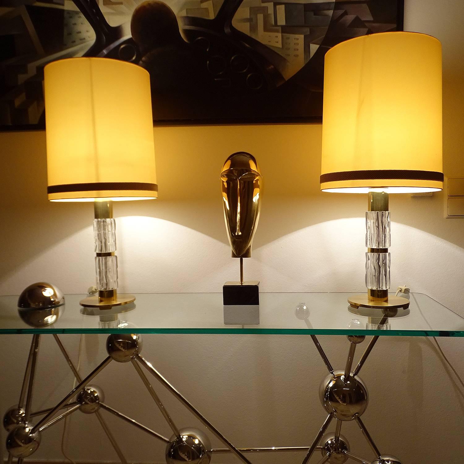 Pair of very large table lamps by Kaiser, circa 1965-1970, featuring a structured glass column with polished and patinated brass accents, large black and gold shade. Wiring: The lamps have been tested with US American light bulbs under 120v and they