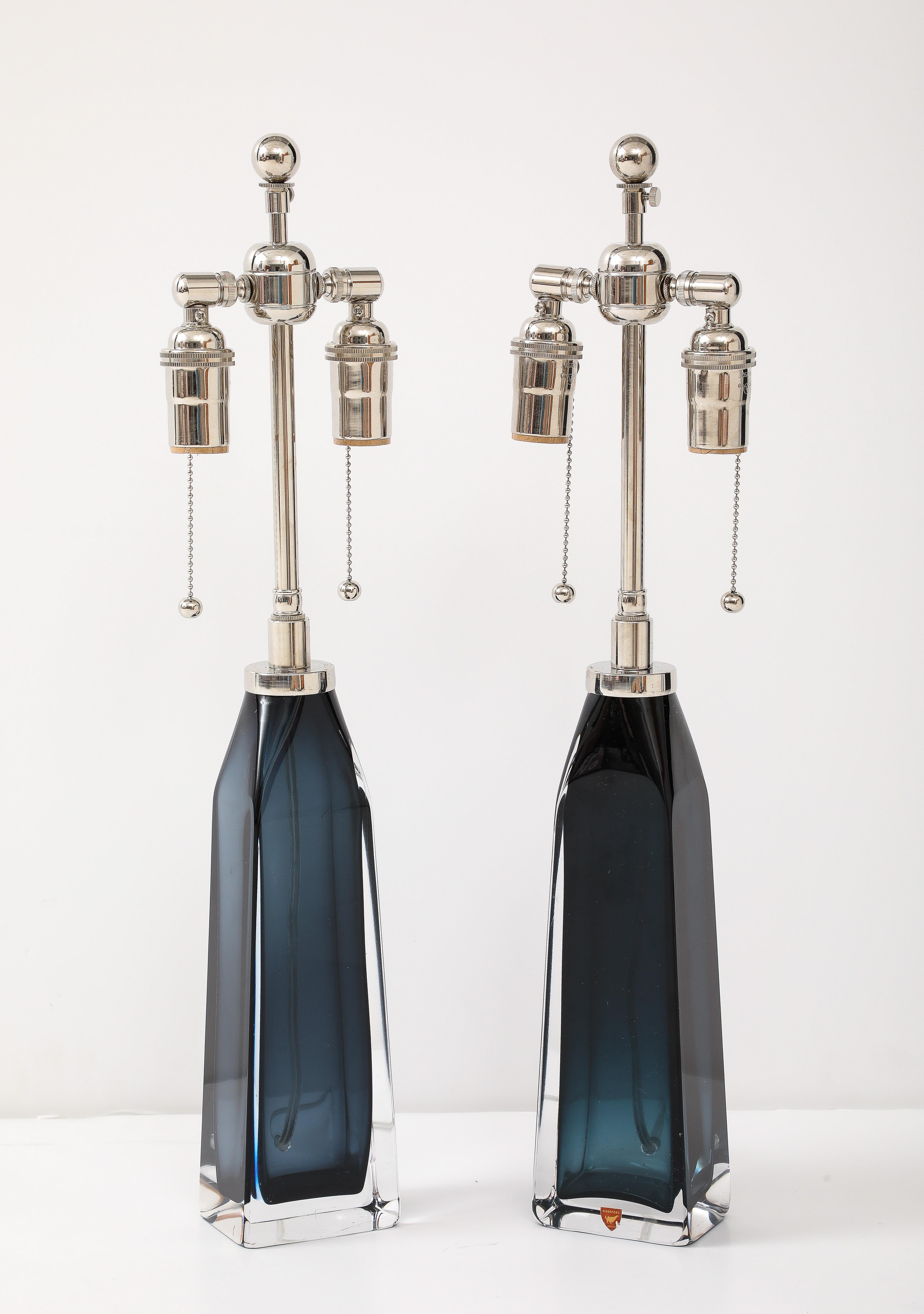 Pair of 1950's large Mid Night Blue glass lamps  designed by Carl Fagerlund for Orrefors.
The lamps are In. Wonderful condition and Have been Newly rewired for the US with adjustable polished Nickel double clusters that take standard size light