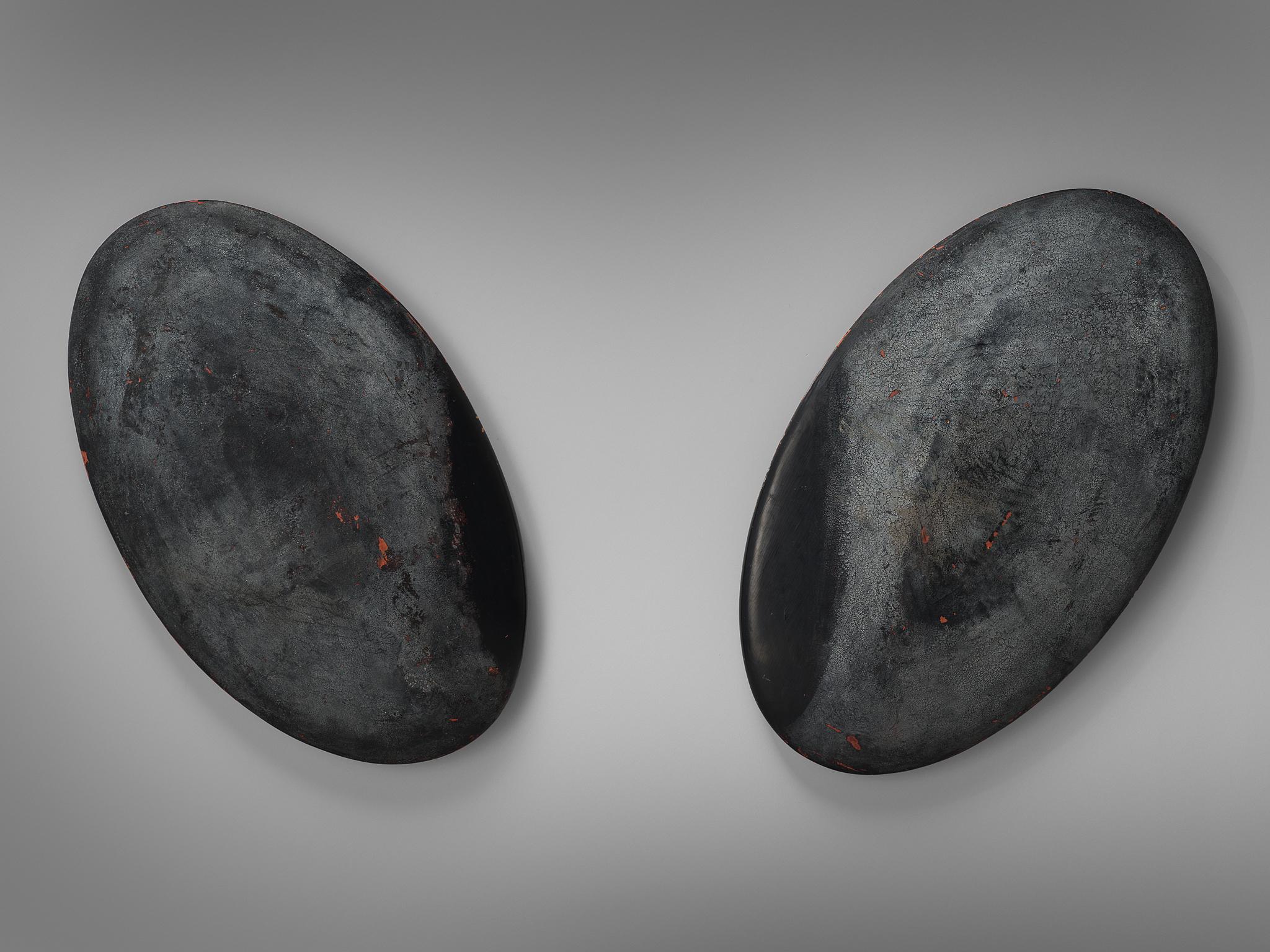 Pair of oval wall sculptures, solid wood, paint, Europe, 1960s.

This dense set of organic sculptures have a stone like shape. They differ throughout each piece in textures because of layered paint and smooth areas. These moody pieces have traits of