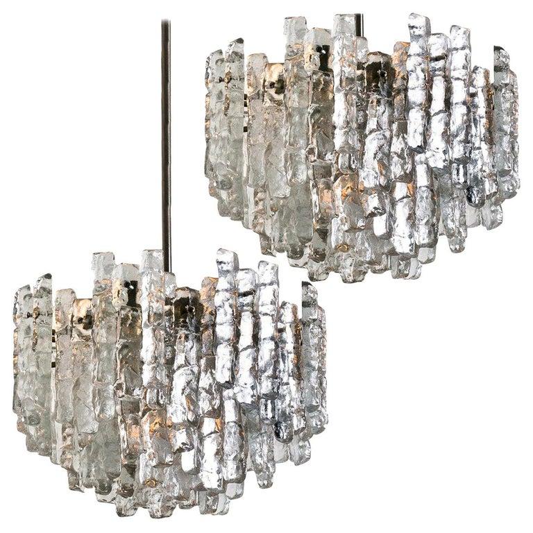 This modern chandeliers, manufactured by Kalmar Austria in the 1970s, have eight E27 sockets and three layers of textured solid ice glass sheets dangling from it. This unique chandeliers are not only functioning as light source but also as a