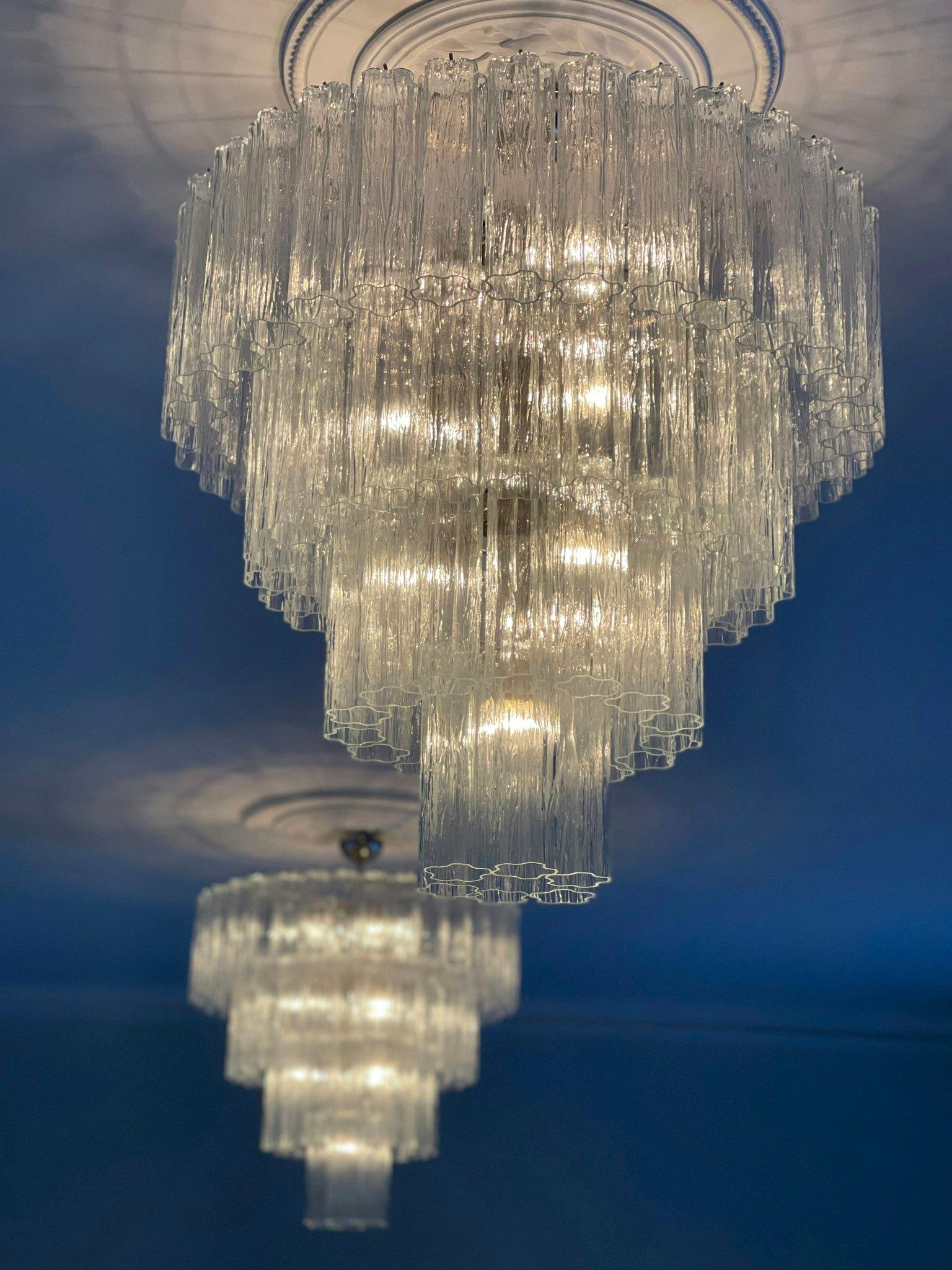Pair of Large Murano Glass Chandelier with Tubular Glass Prisms.  Contemporary Chandeliers in Traditional Italian Mid-Century Style.
The chandeliers are composed of 77 Transparent Crystal Elements in the size of 25 x7 cm (9.9