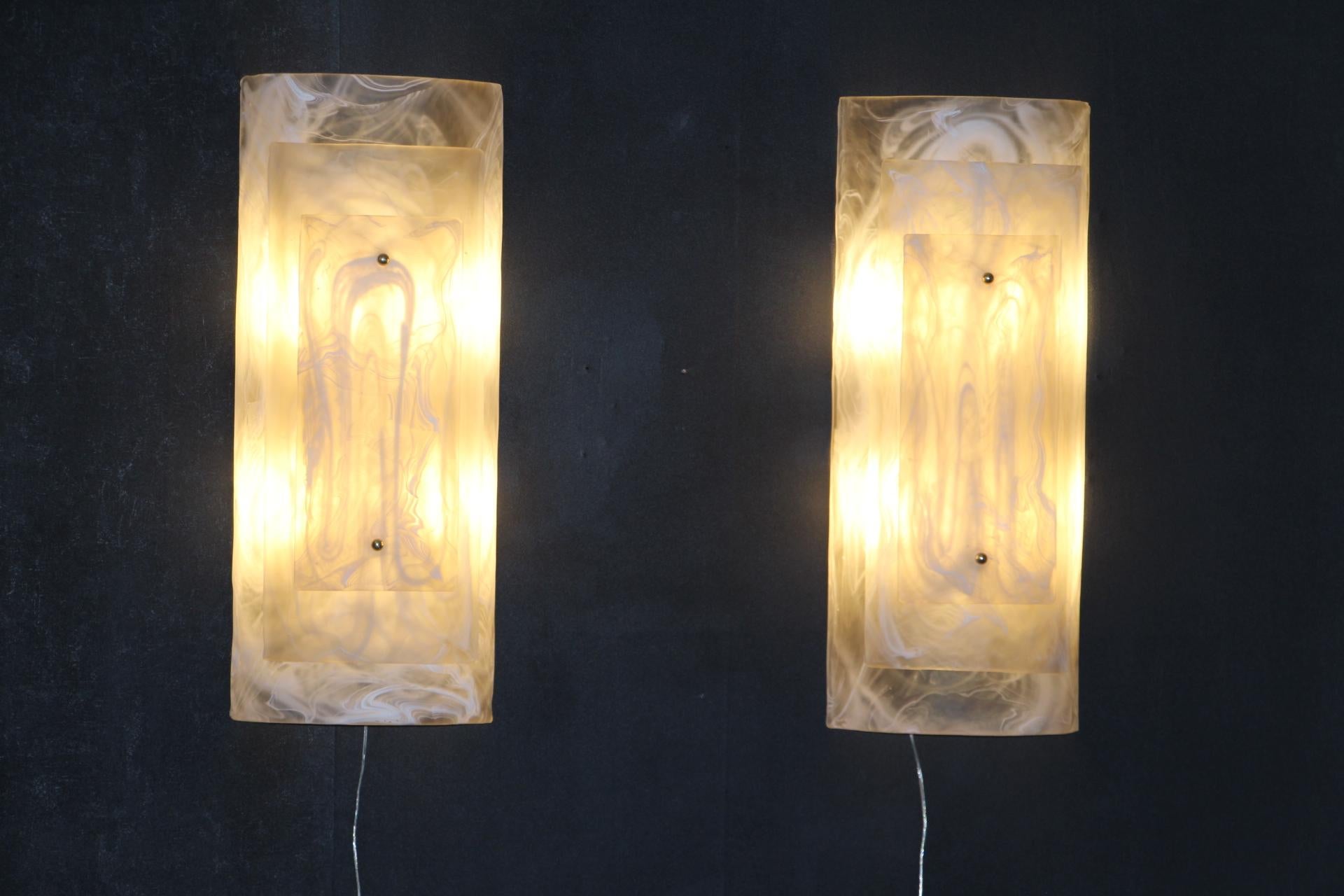 This impressive pair of murano glass sconces is really unusual.
They are made of 3 layers of bent glass, one fixed on the other thanks to 2 brass studs. 
Pieces of glass are an art work, looking like alabaster or marble design.
They are in the style