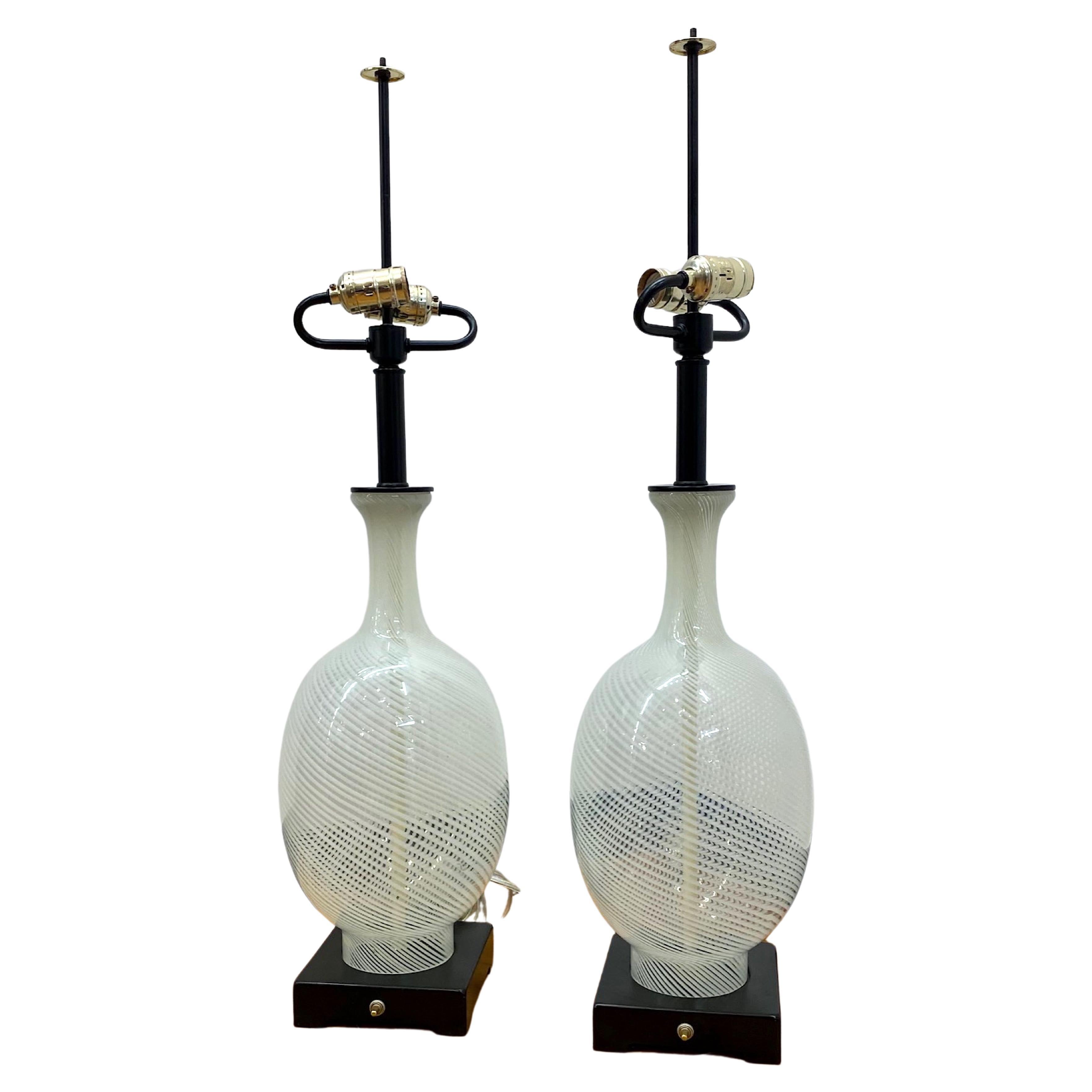 A lovely and large pair of 1960s hand blown clear and white stripe glass vase table lamps from Murano, Italy. Each glass piece is blown with an open top and bottom to allow for it to be mounted as a lamp. The central rod with in white inside the