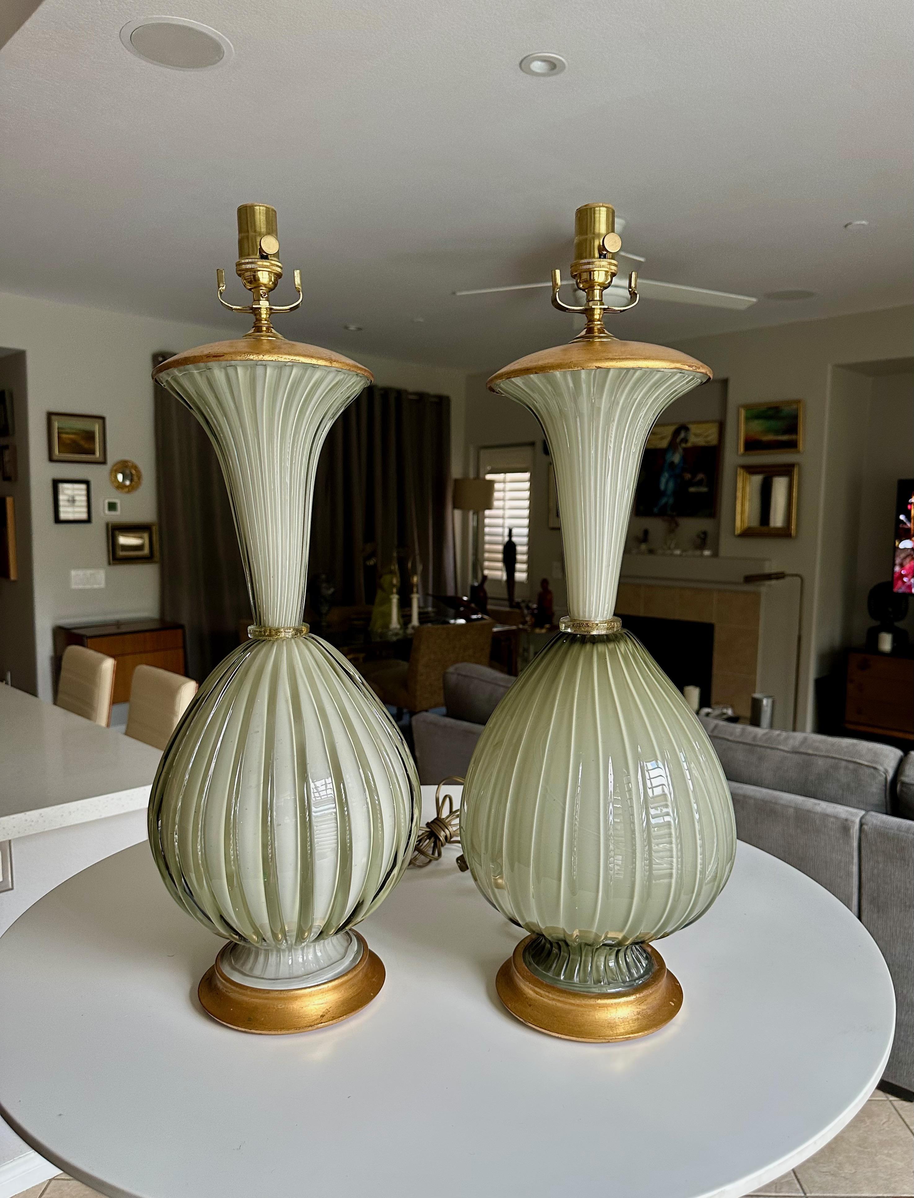 Paire similaire de grandes lampes de table en verre coloré soufflé à la main à Murano, de couleur gris olive et strié, par Marbro. Les lampes en verre épais et lourd reposent sur des bases en bois doré personnalisées, avec des capuchons de vase en