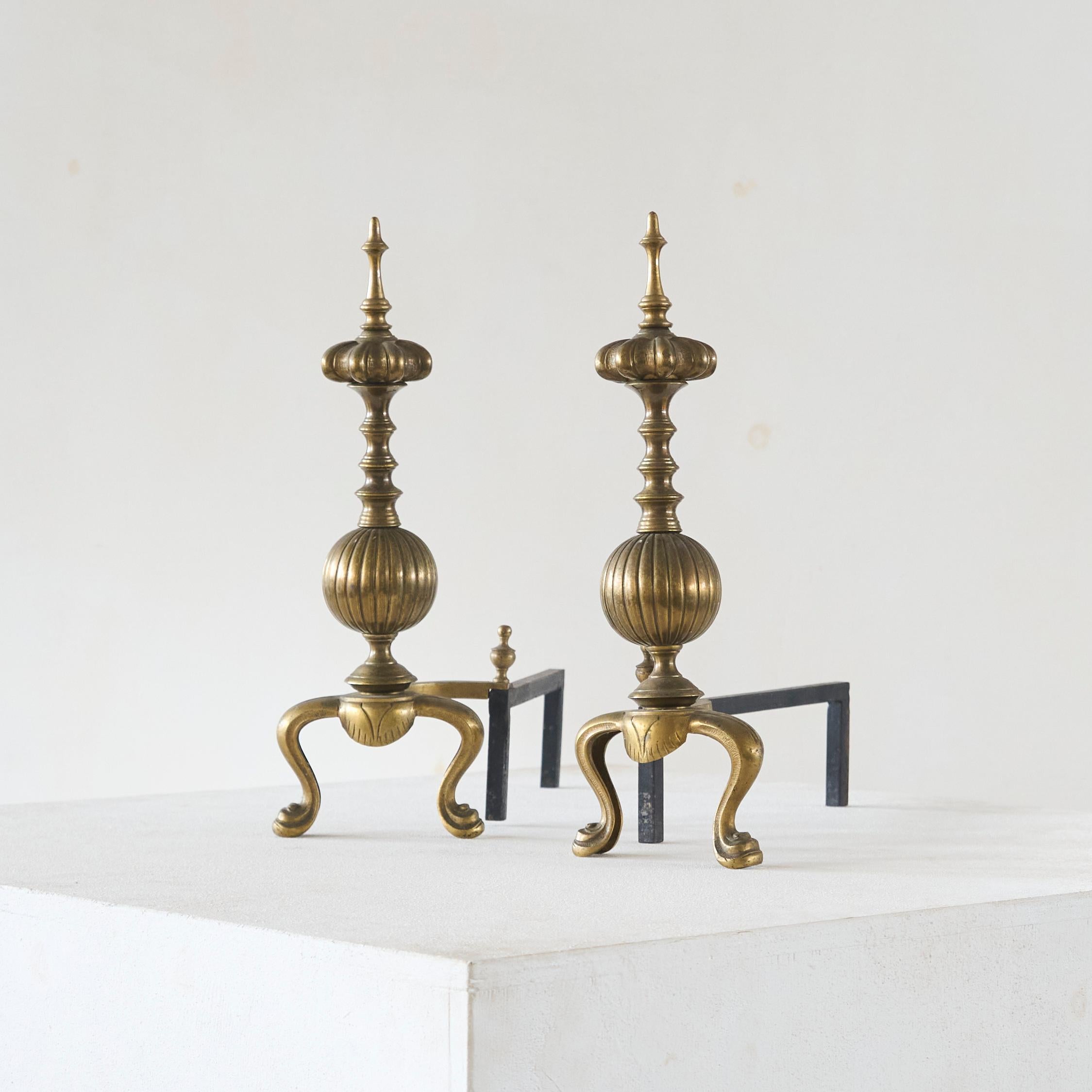 Pair of Large Neoclassical Andirons in Patinated Brass. Europe, mid to late 19th century.

A large and imposing pair of andirons or fire dogs in patinated brass and wrought iron. Featuring an impressive design, these andirons have a truly majestic