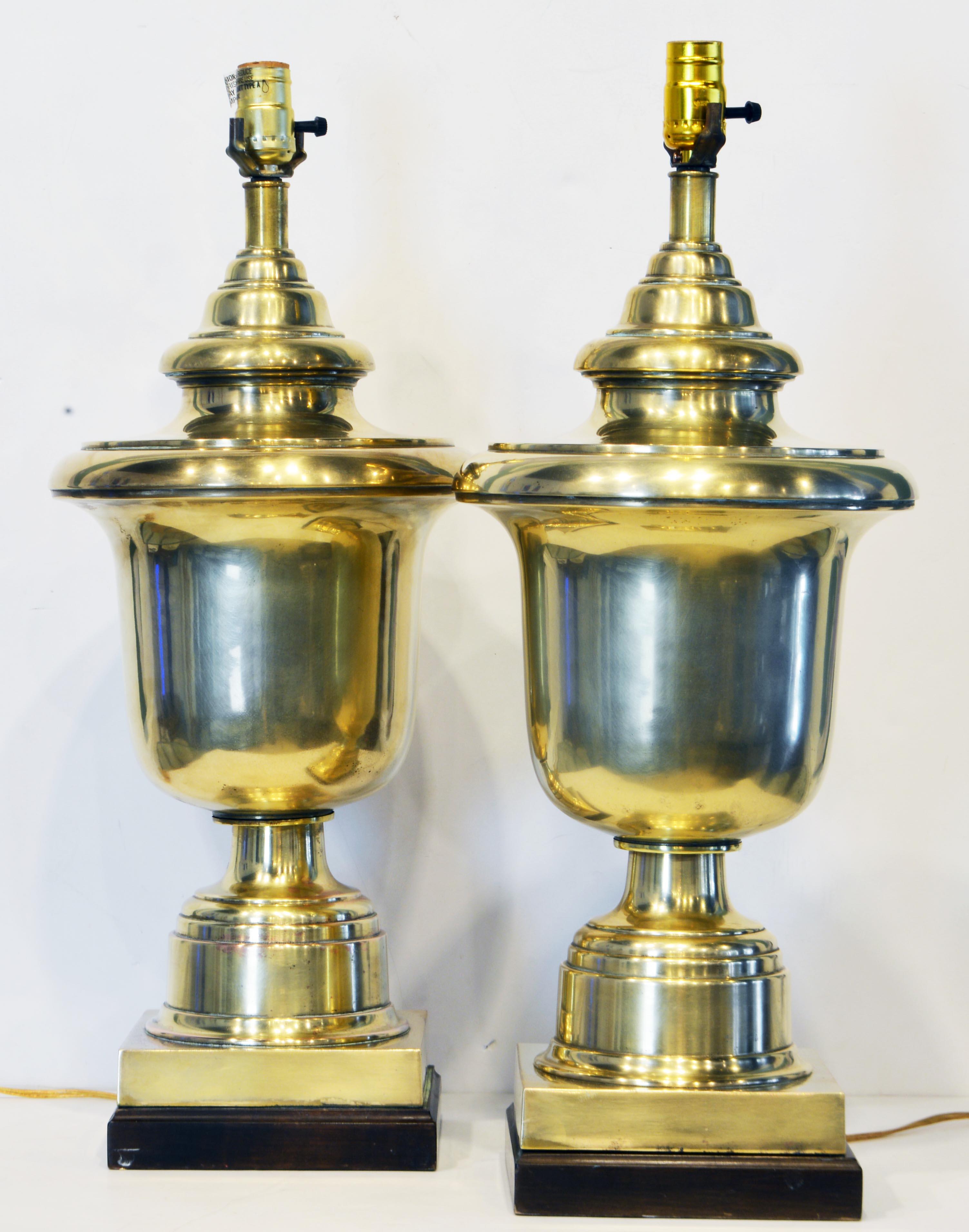This pair of stately urn shaped solid brass table lamps feature large neoclassical style urns on square ebonized bases. As shown without shades they stand 26 inches tall making an impressive statement.