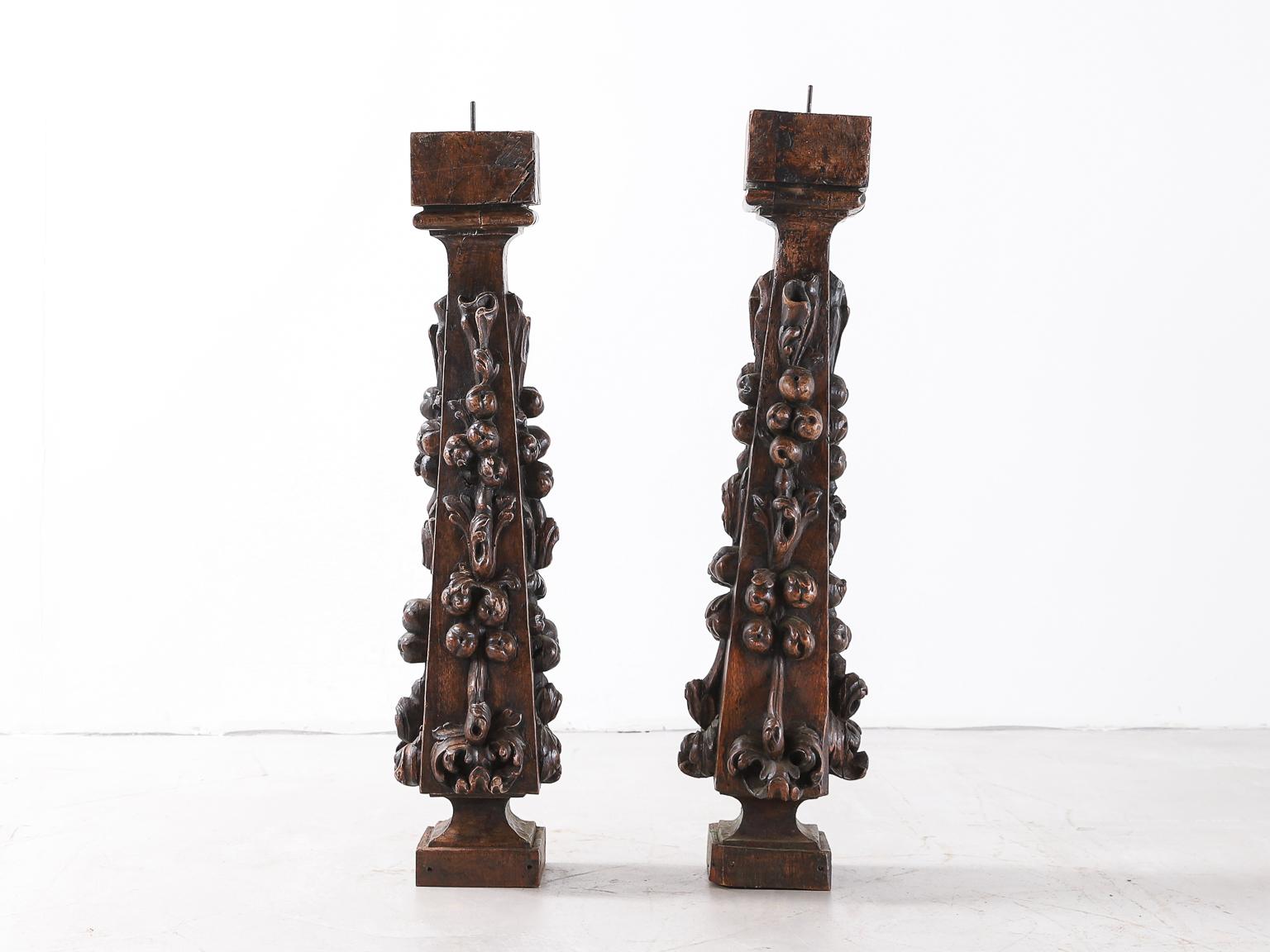 An intricately carved pair of large oak Renaissance period candlesticks. Beautifully patinated dark oak with expertly carved berries and leaves from base to top on three sides.