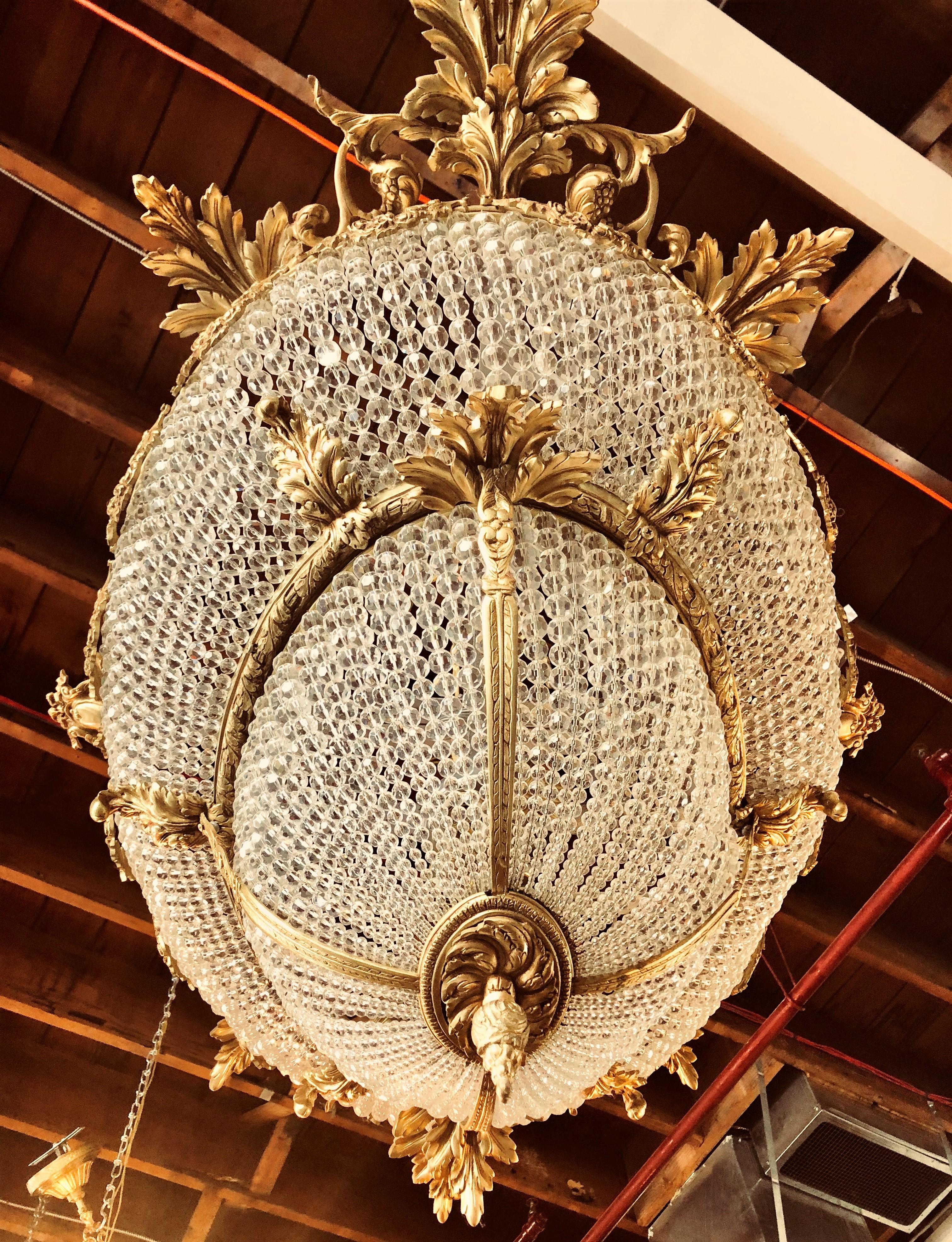 A pair of oval double bowl shaped bronze and crystal basket chandeliers. This palatial pair of Louis XI style chandeliers are simply spectacular in scale, form and quality. Each double crystal basket set and framed in a doré bronze having wonderful