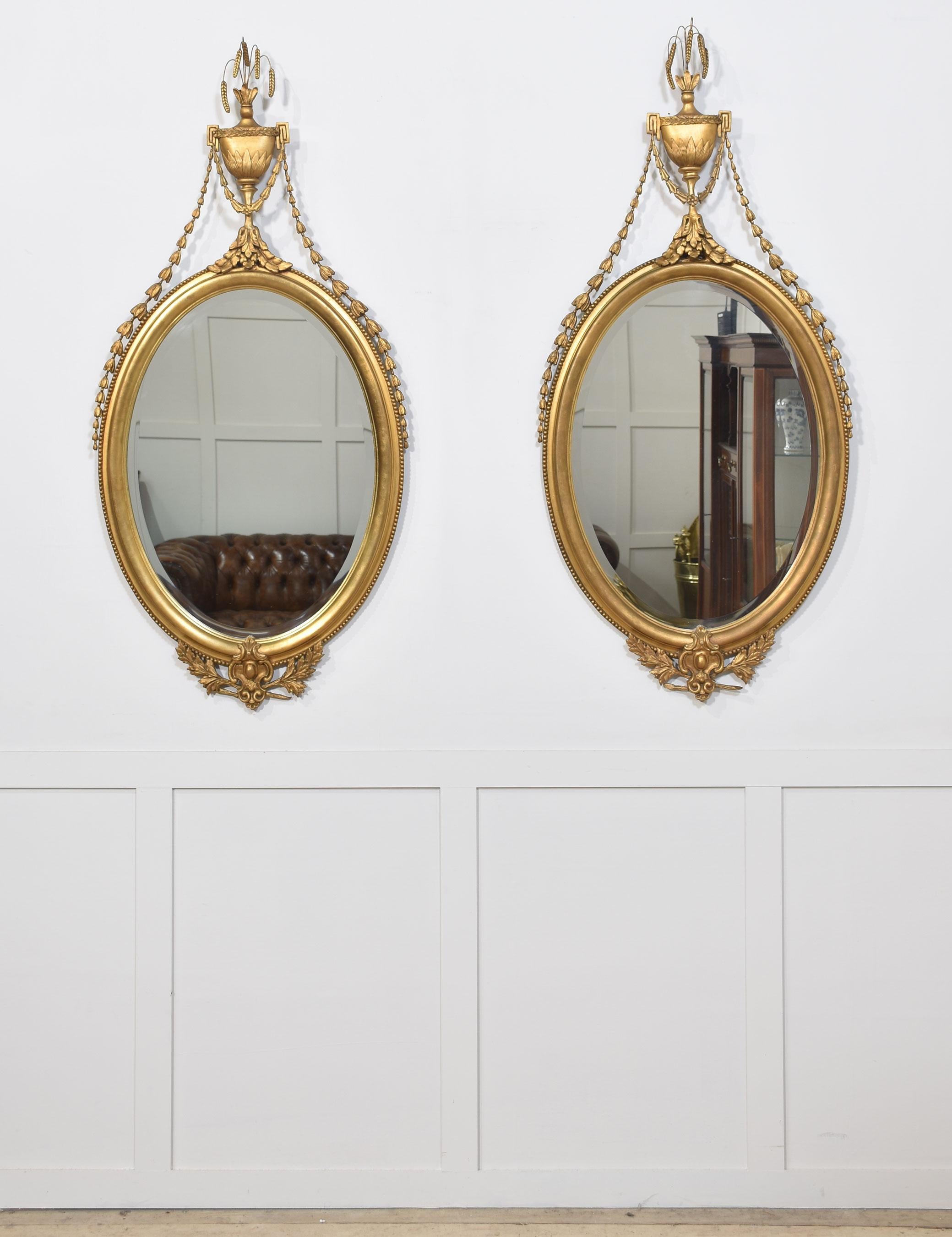 Pair of Georgian style wall mirrors, with catkin and urn pediment supporting the bell flower crestings. To the large central oval bevelled mirror plate above the foliated apron.
Dimensions
Height 52.5 Inches
Width 24.5 Inches
Depth 3.5 Inches
