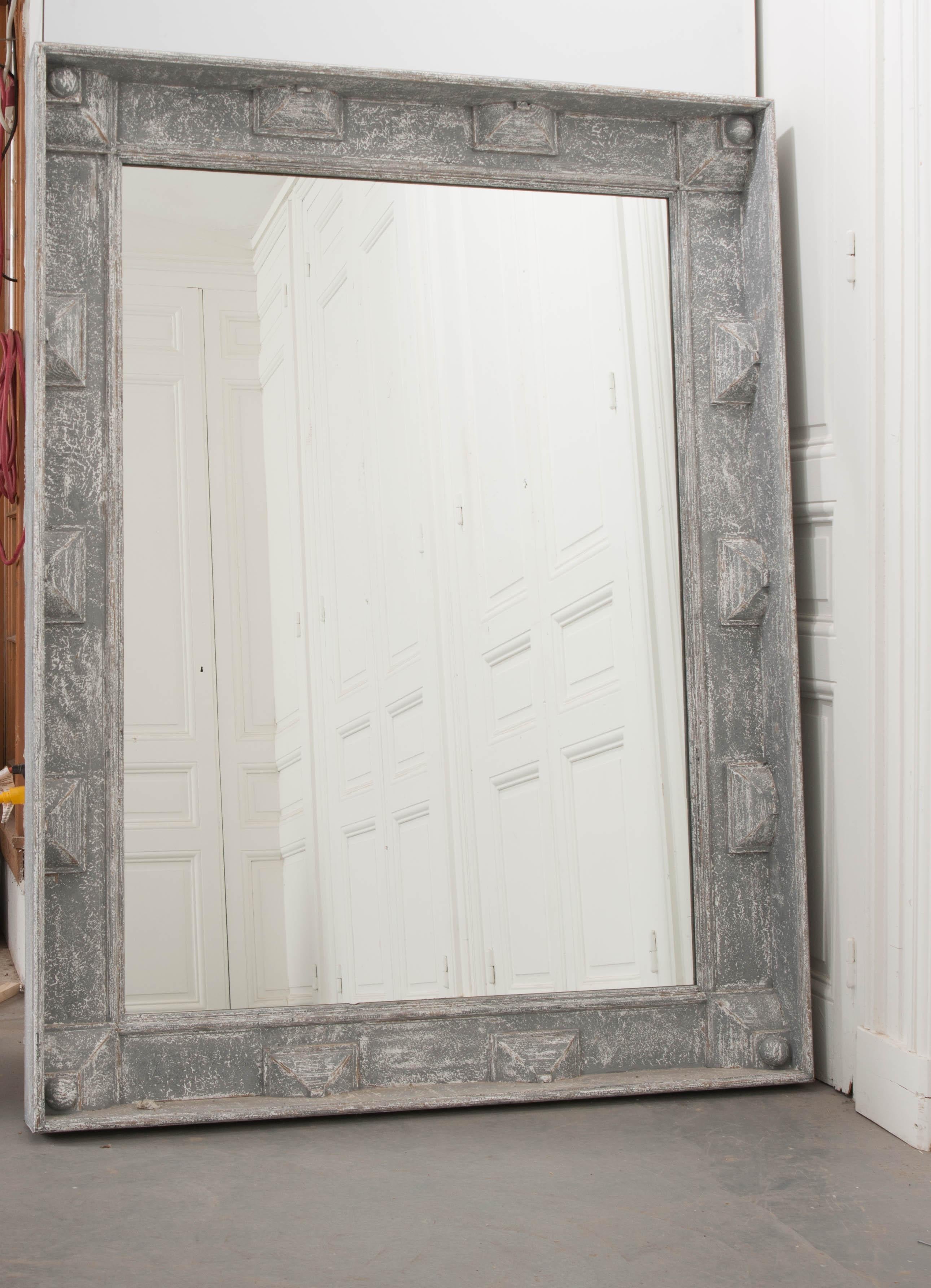 A grand pair of new, reproduction mirrors that have been painted a fabulous blue-gray and have frames crafted with excellent geometric carvings. Each large mirror contains new glass that is encased by its interesting, deep frame. The pair can be