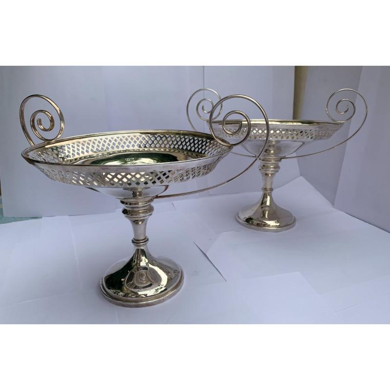 In good vintage condition, they have some marks commensurate with age. 

They stand on round pedestal bases and  have beautifully curved handles.
They have lovely geometric, pierced openwork and make a striking pair.
Hallmarked: Made by Walker &