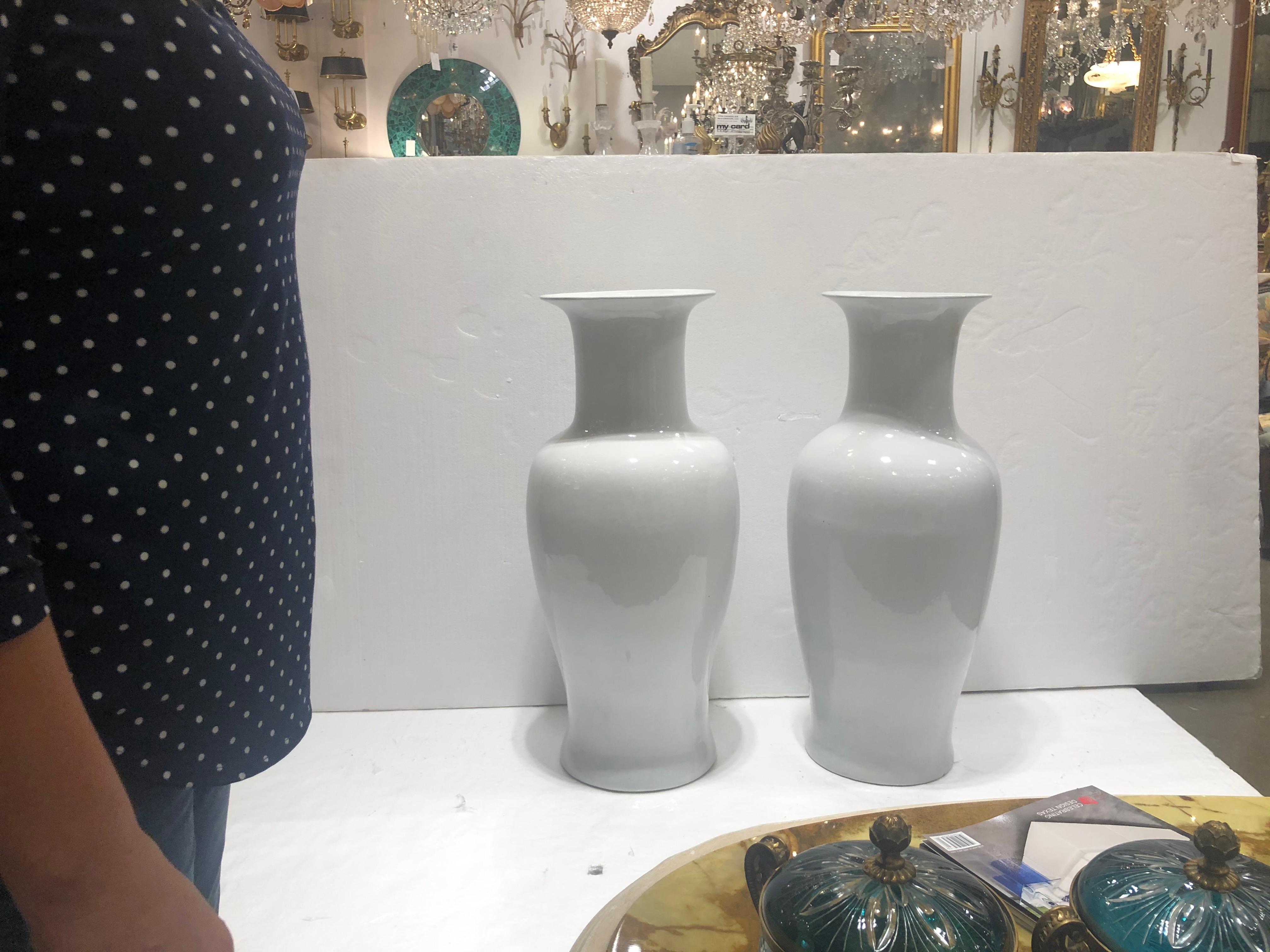 A pair of large porcelain vases in an overall white hue and completed with a gloss glaze.
CIRCA: 20th Century.