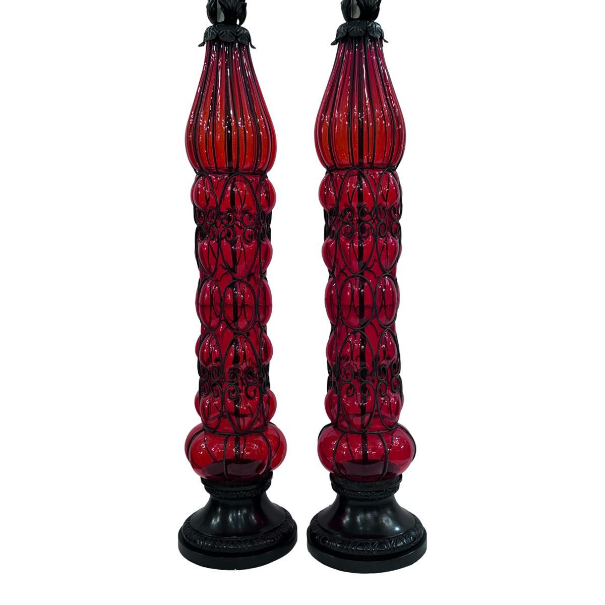 Paire de grandes lampes en verre soufflé vénitien des années 1960, avec cadre en fer entourant le corps en verre.

Mesures :
Hauteur du corps : 37