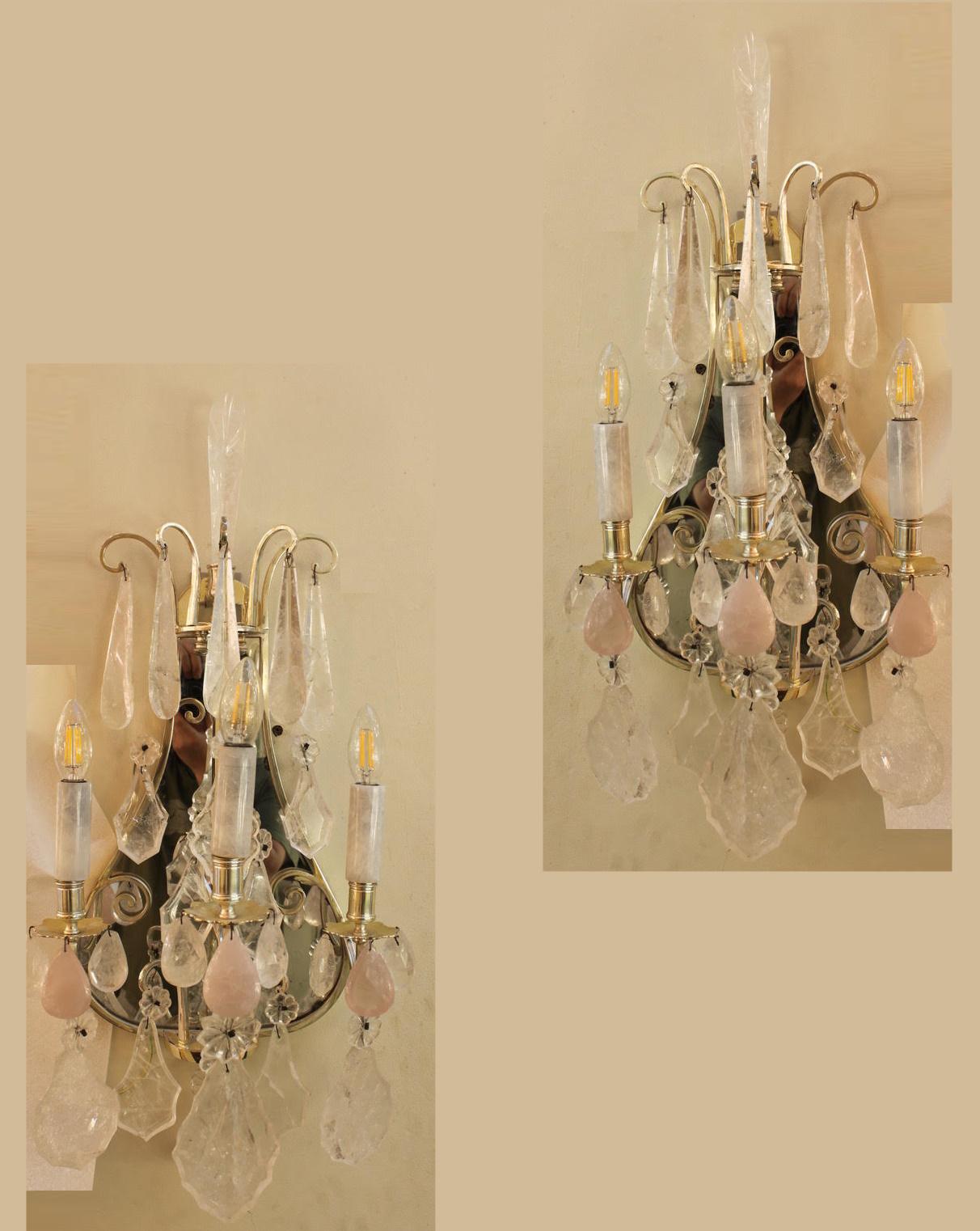 A beautiful pair of mirror backed wall lights in silver gilt with 3 lights profusely hung with large rock crystal plaques and lozenges. Also featuring pebble rose quartz drops and  additional clear rock quartz drops. A magnificent example of its