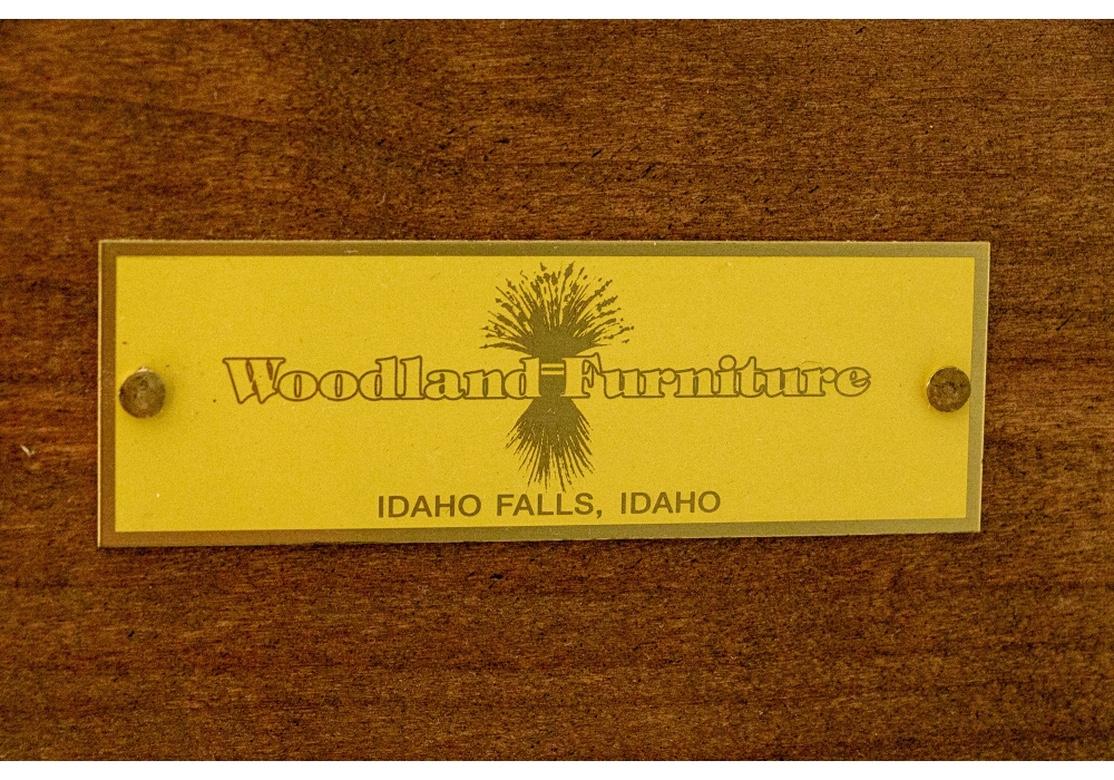 Impeccable craftsmanship by Woodland Furniture, Idaho Falls, Idaho. Fine construction in an ebonized antiqued finish. With a cavetto cornice over a carved arch shaped case with three pale painted shelves and back. The lower cabinet with three long