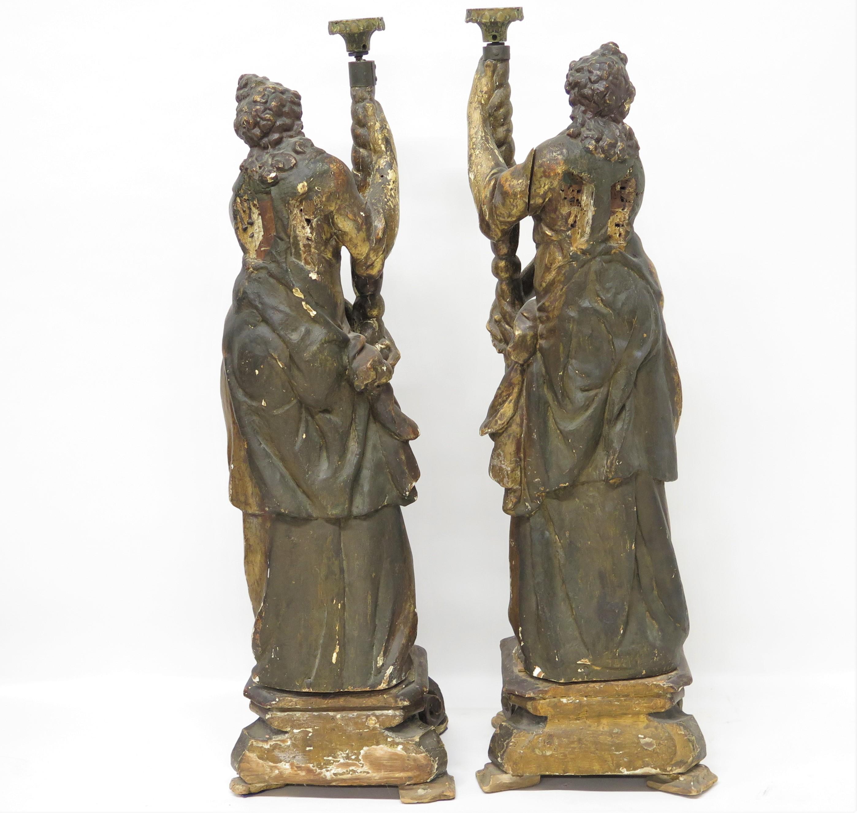 a large scale pair of Italian polychromed, carved and gilded figural candlesticks in the form of angels, Italy. 18th century
