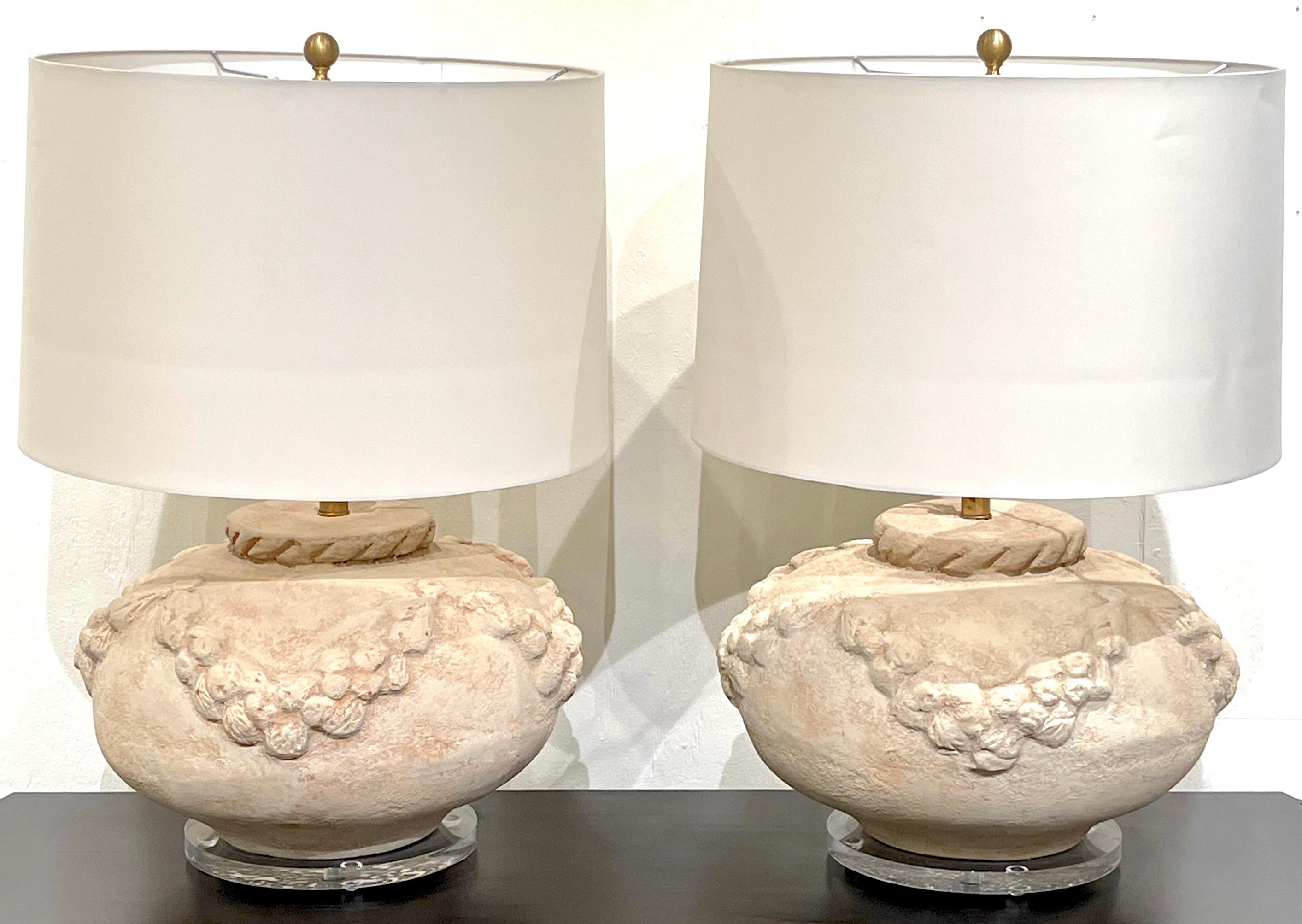 Paire de lampes néoclassiques italiennes en terre cuite et lucite 
Italie, Circa 1980

Chacun est un vase substantiel décoré d'une guirlande continue, monté sur un piédestal en lucite de 10 pouces de diamètre. Illustré avec des abat-jour de 19