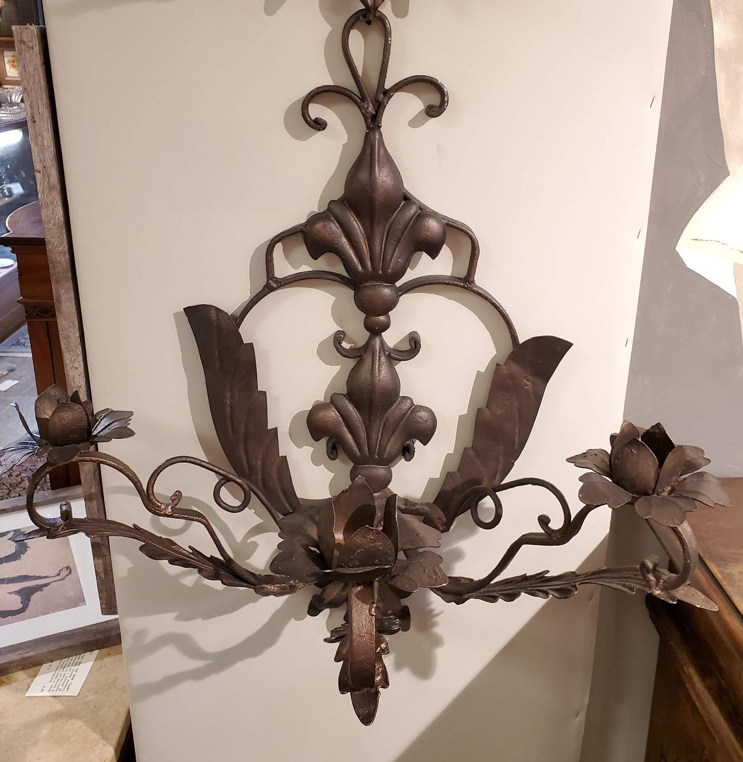 An enchanting pair of large-scale hand-forged iron wall sconces from Italy, circa 1890. Beautifully crafted in the late 19th century, these Italian sconces feature scrolling arms with stylized floral candle cups and finely worked foliate details
