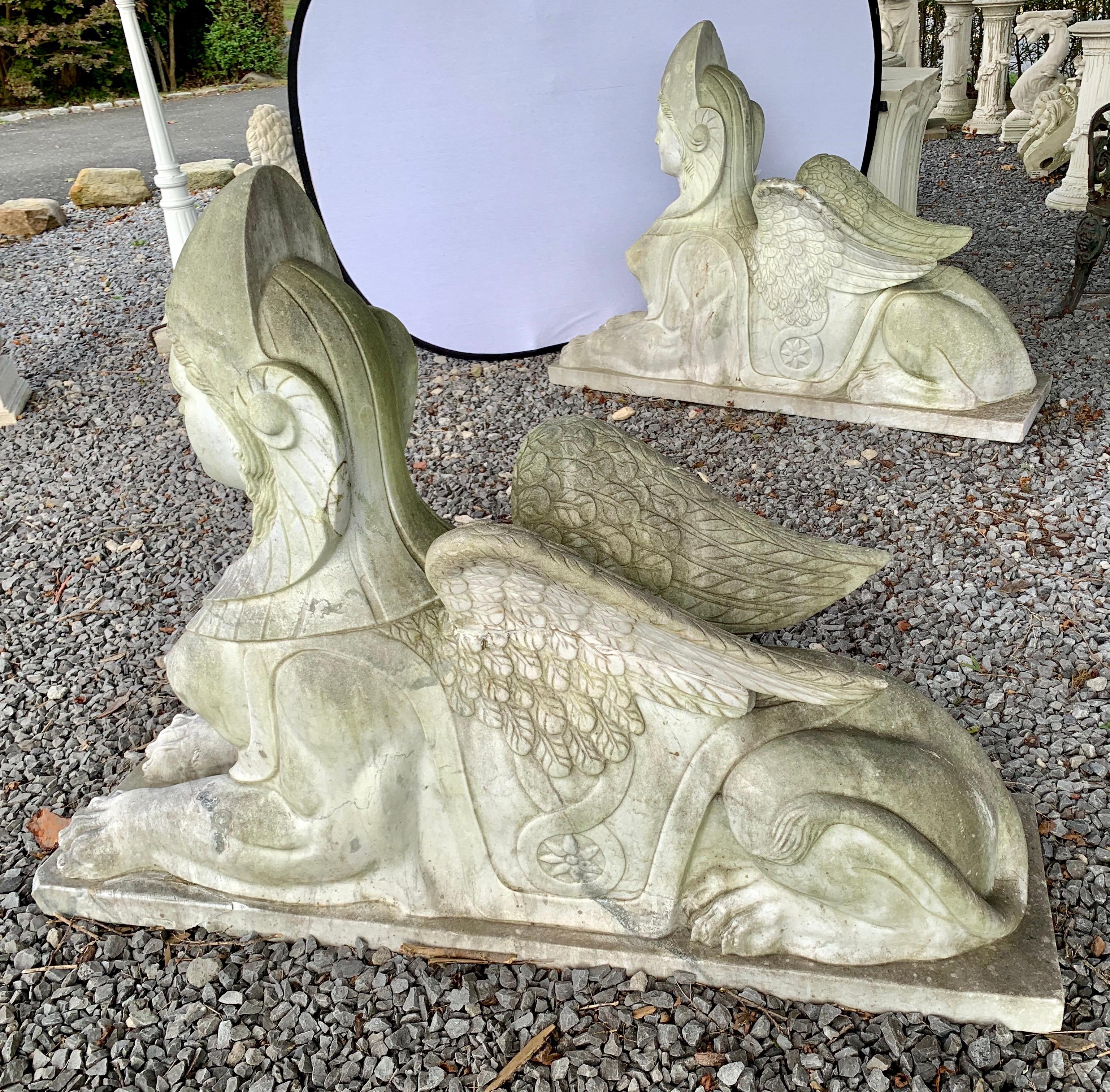 Stunning pair of early 20th century Egyptian Revival marble garden sphinxes. Each have female heads and drapery on lion bodies. From one of the finest homes on Long Island. They each weigh several hundred pounds each. Now, more than ever, home is