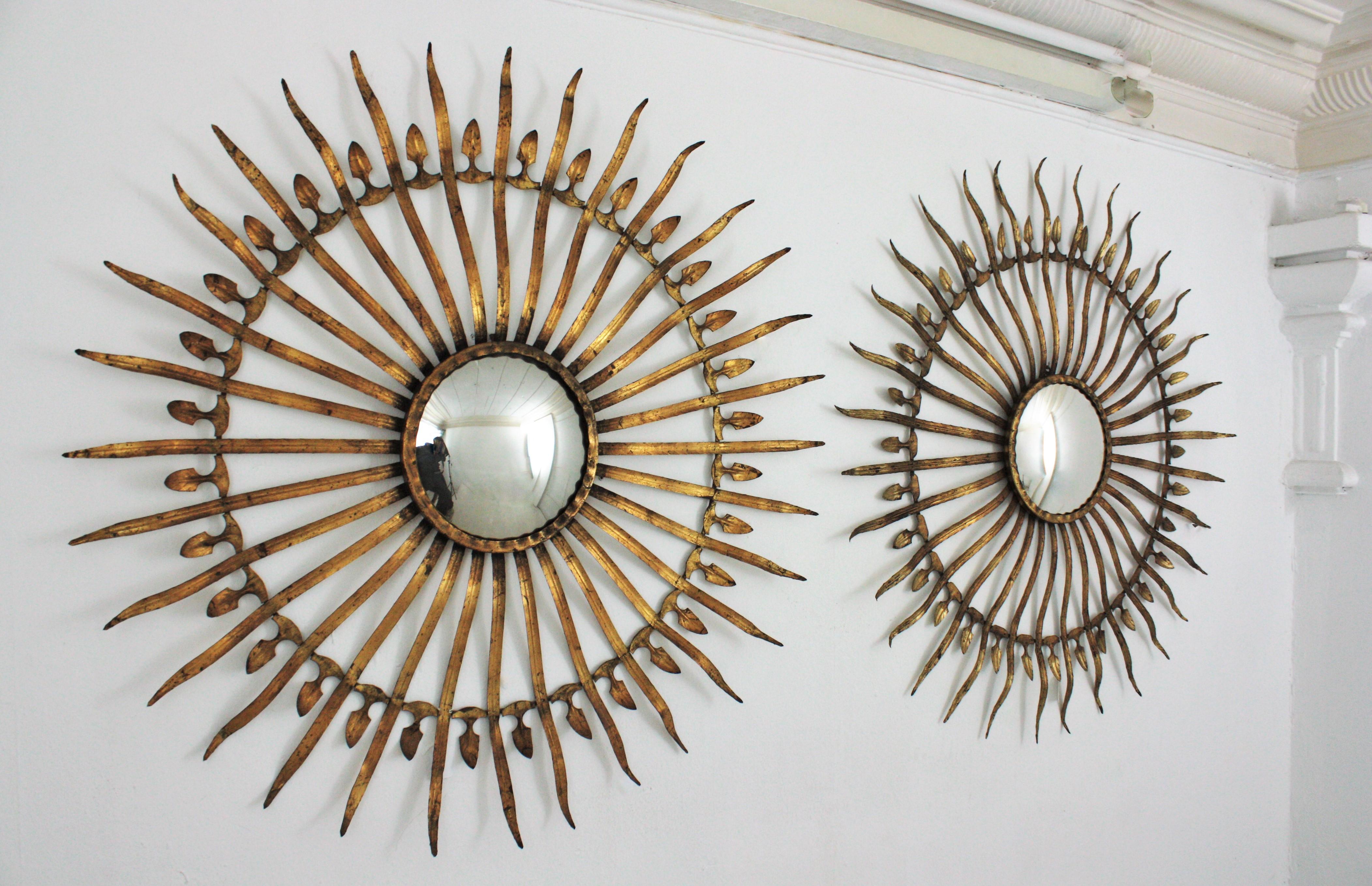 Pair of Spanish 1950s Hollywood Regency oversized gilt iron convex sunburst / starburst mirrors.
Magnificent set of two large scale decorative sunburst mirrors. Handcrafted in iron and finished in gold leaf gilding.
They have a terrific aged patina