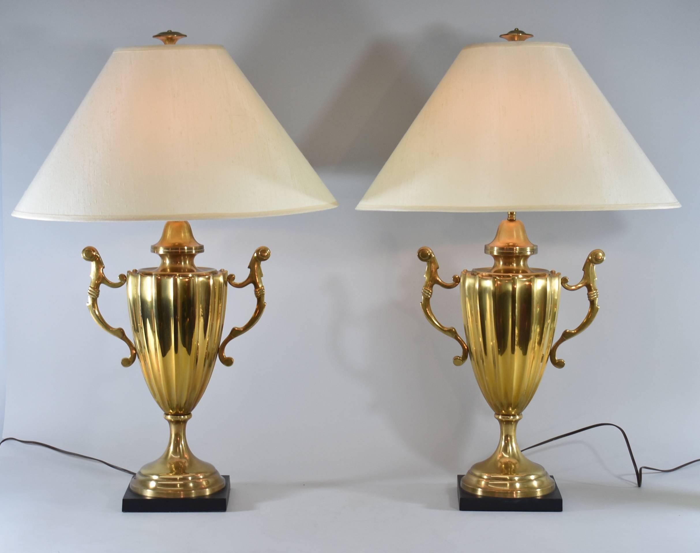 A beautiful pair of large-scale table lamps by Chapman, 1985. They feature a brass urn shaped body with handles and a black metal base. Perfect for any room in your home.