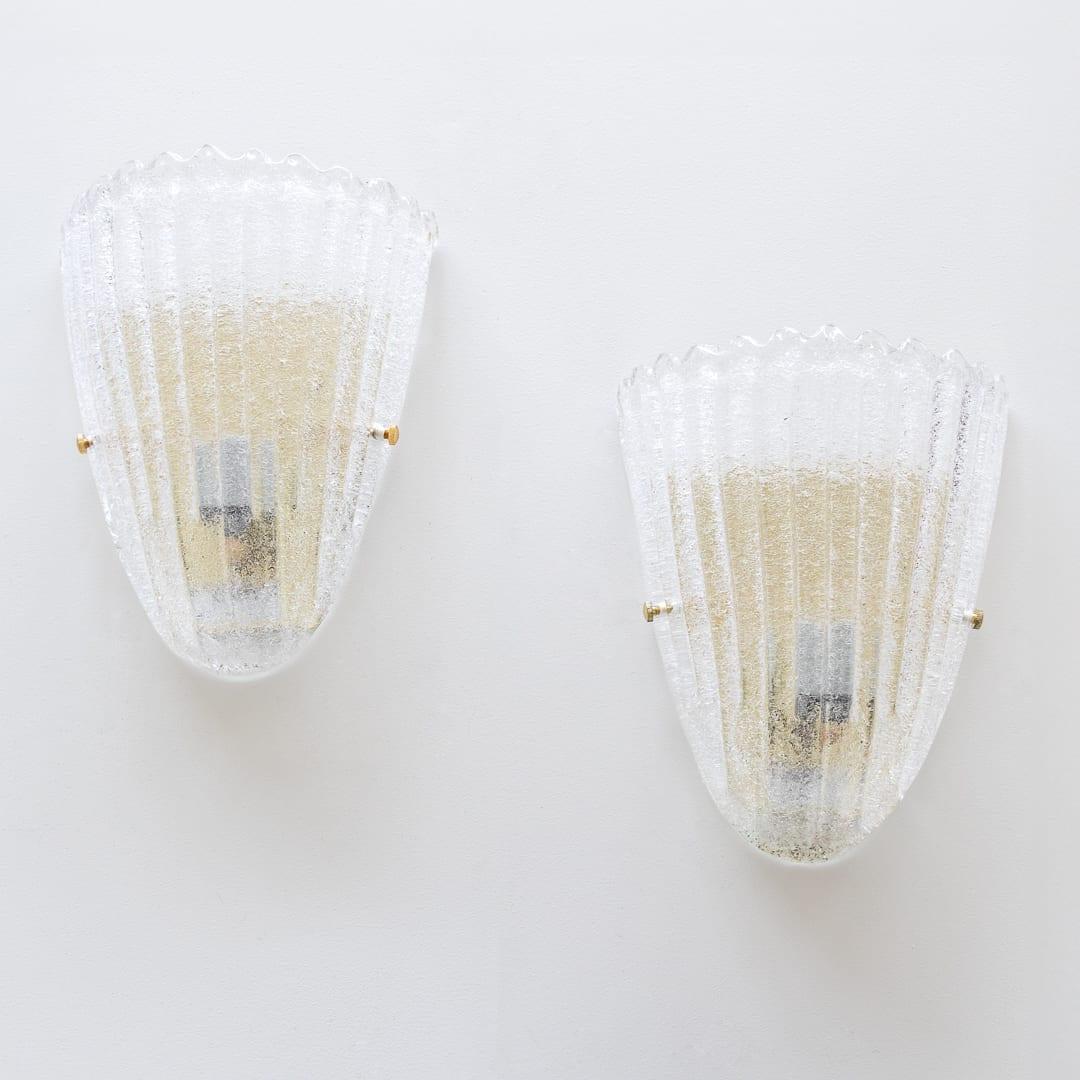 Beautiful pair of large glass sconces with scalloped top edge from Italy, 1960's. Ribbed clear class with brass back plate. Newly rewired with single socket in each. Illuminates beautifully. Sold as a pair. Two pairs available. Each takes one E26