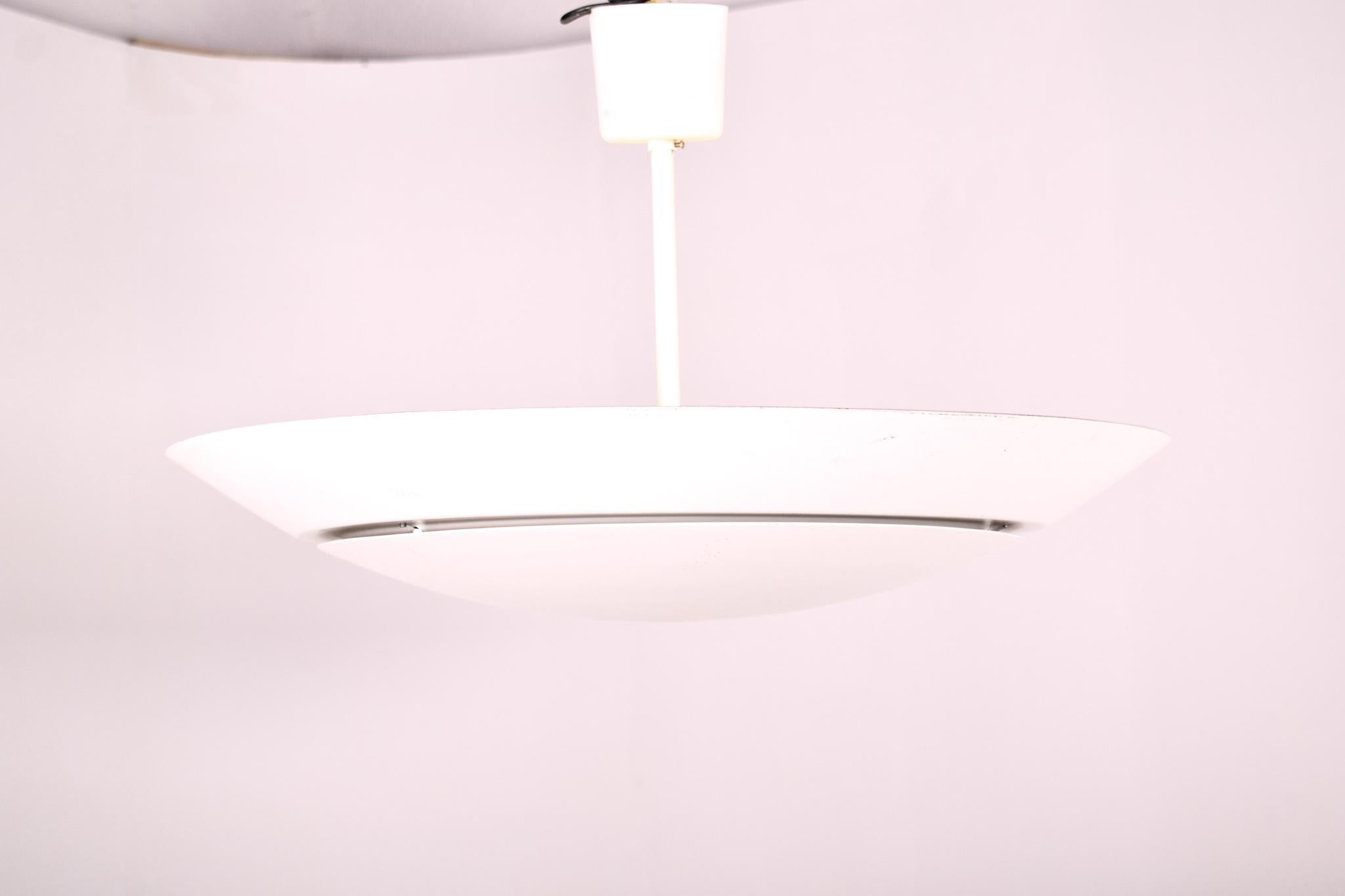 This pair of large Scandinavian mid-century modern ceiling lamps exudes the sleek and functional design ethos that is a hallmark of 20th-century European design. Constructed from white lacquered aluminum, these lamps embody the minimalist aesthetic,