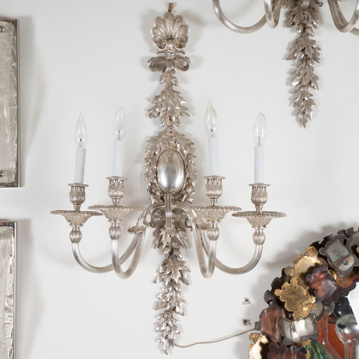 Pair of large silvered bronze candelabra style sconces with cast leaf and shell motif and fluted arms.