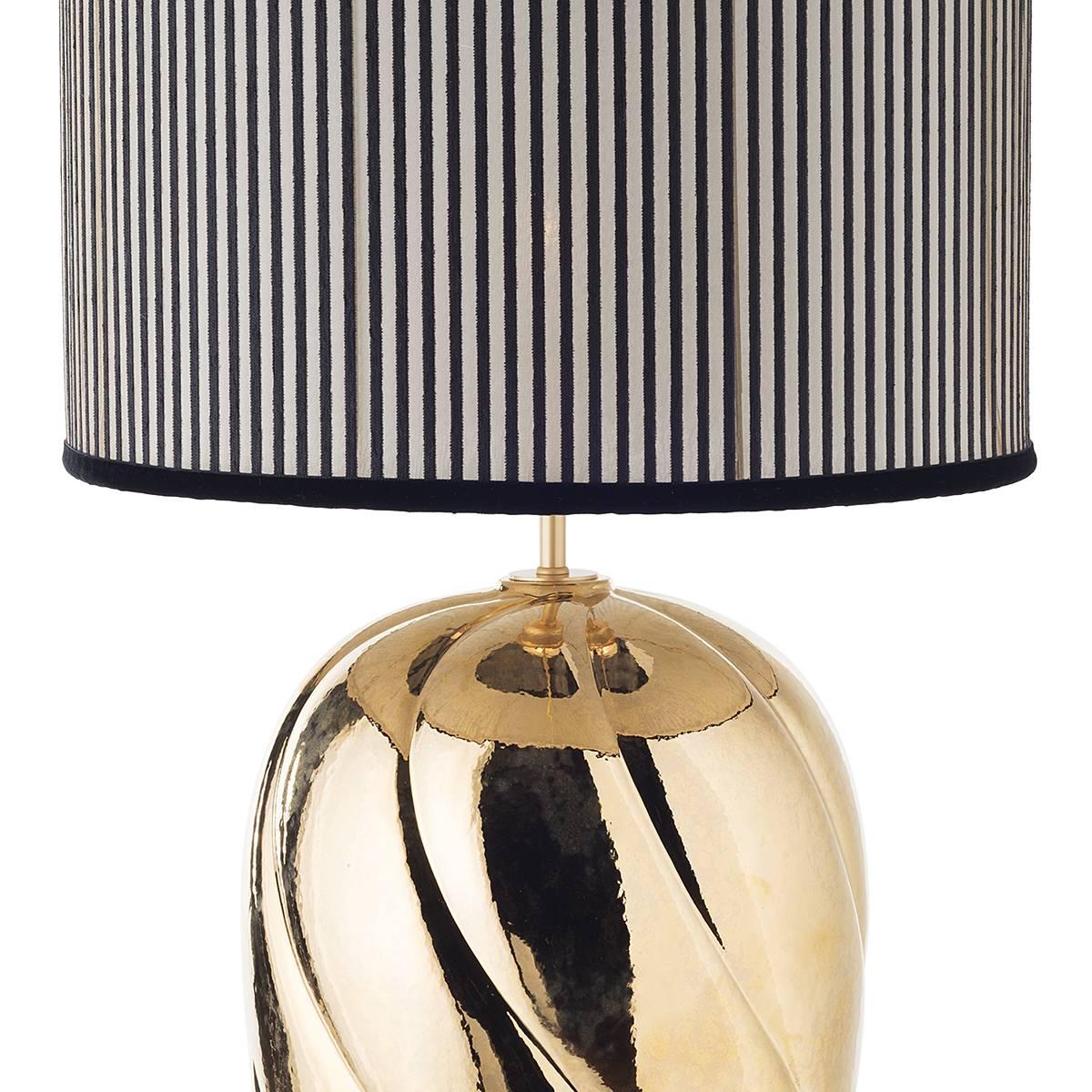 Pair of large ceramic table lamps and shades.
The sinuous-ribbed body made of ceramic is gilded with antique gold hand-painted on dripped glazed surface. The lamp is complemented by a cylindrical shade in a transparent texture enriched by dark