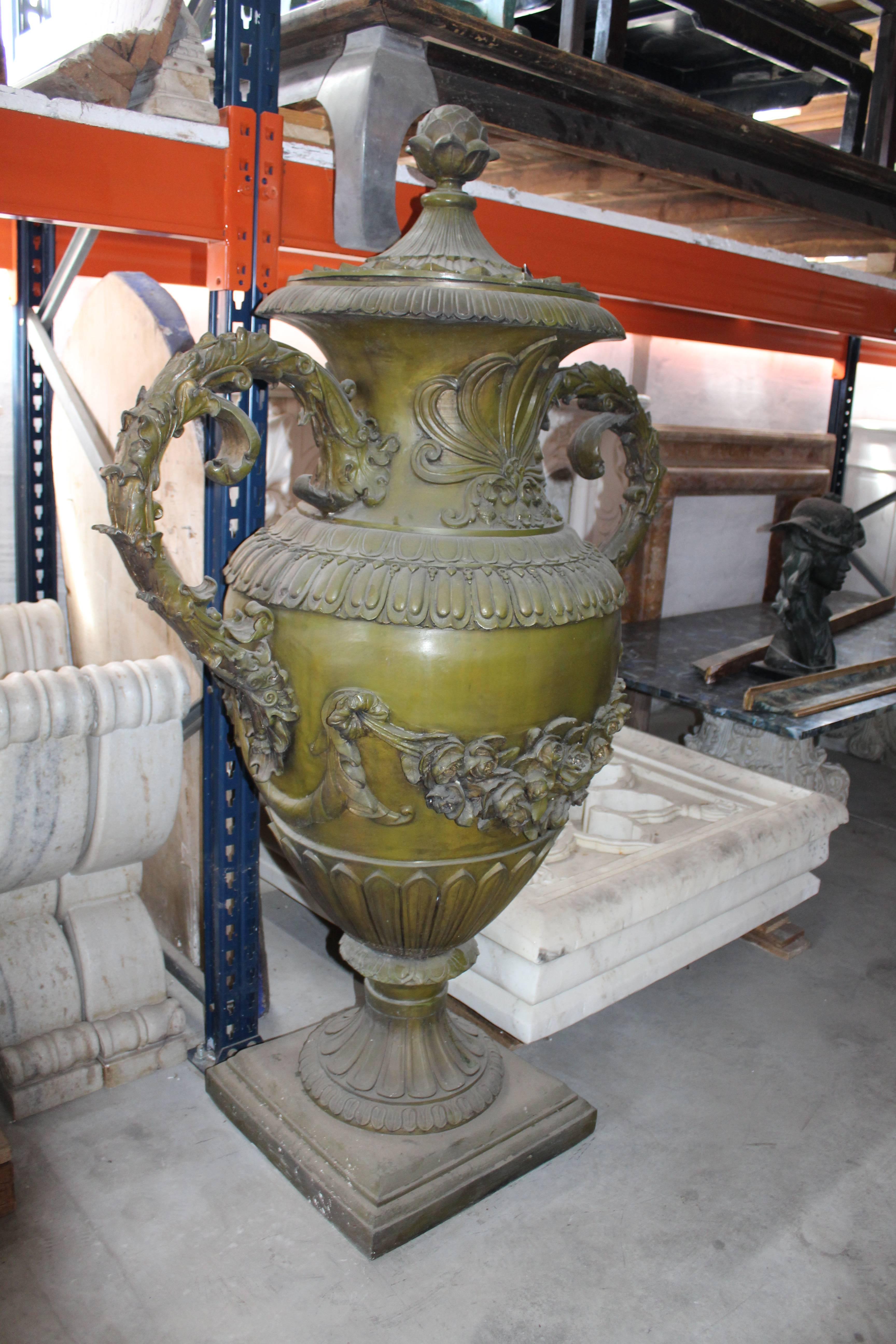 Pair of bronze urns cast using the lost wax technique, with lid and handles, decorated with strings of flower garlands.