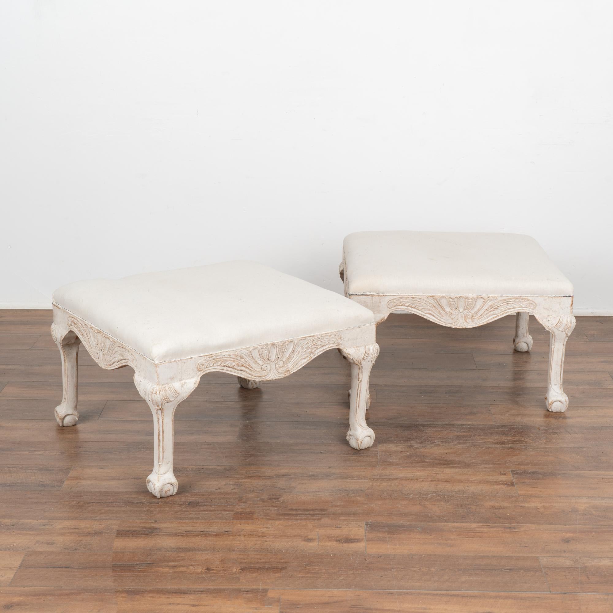 This lovely pair of Gustavian style Swedish stools are a special find due to their large size and square shape. They each rest on carved legs with ball and claw feet while intricate carving along the skirt also adds an elegant touch to the